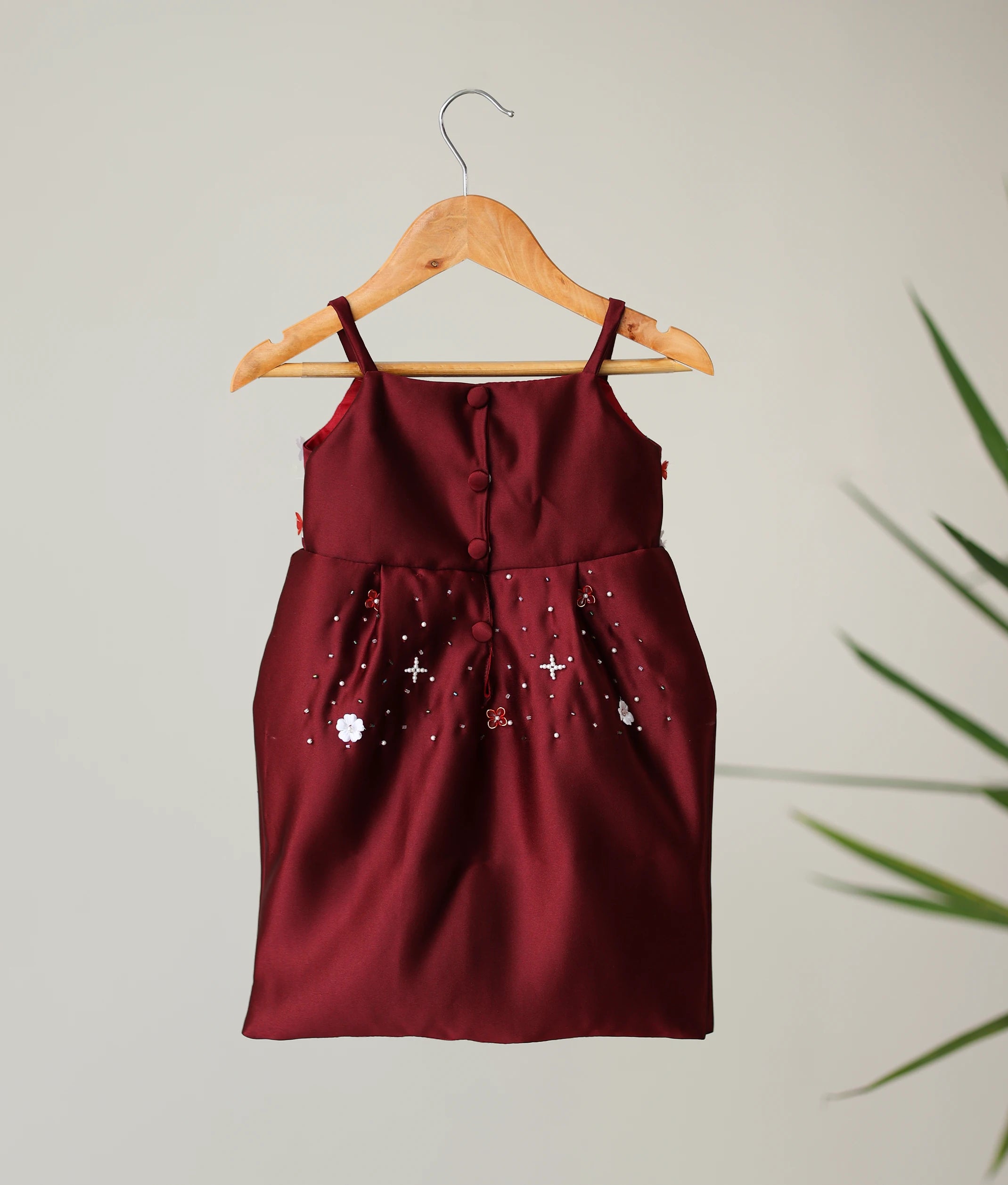 Back view of the maroon below-knee-length baby girl dress, highlighting the satin texture and shirt button closure.