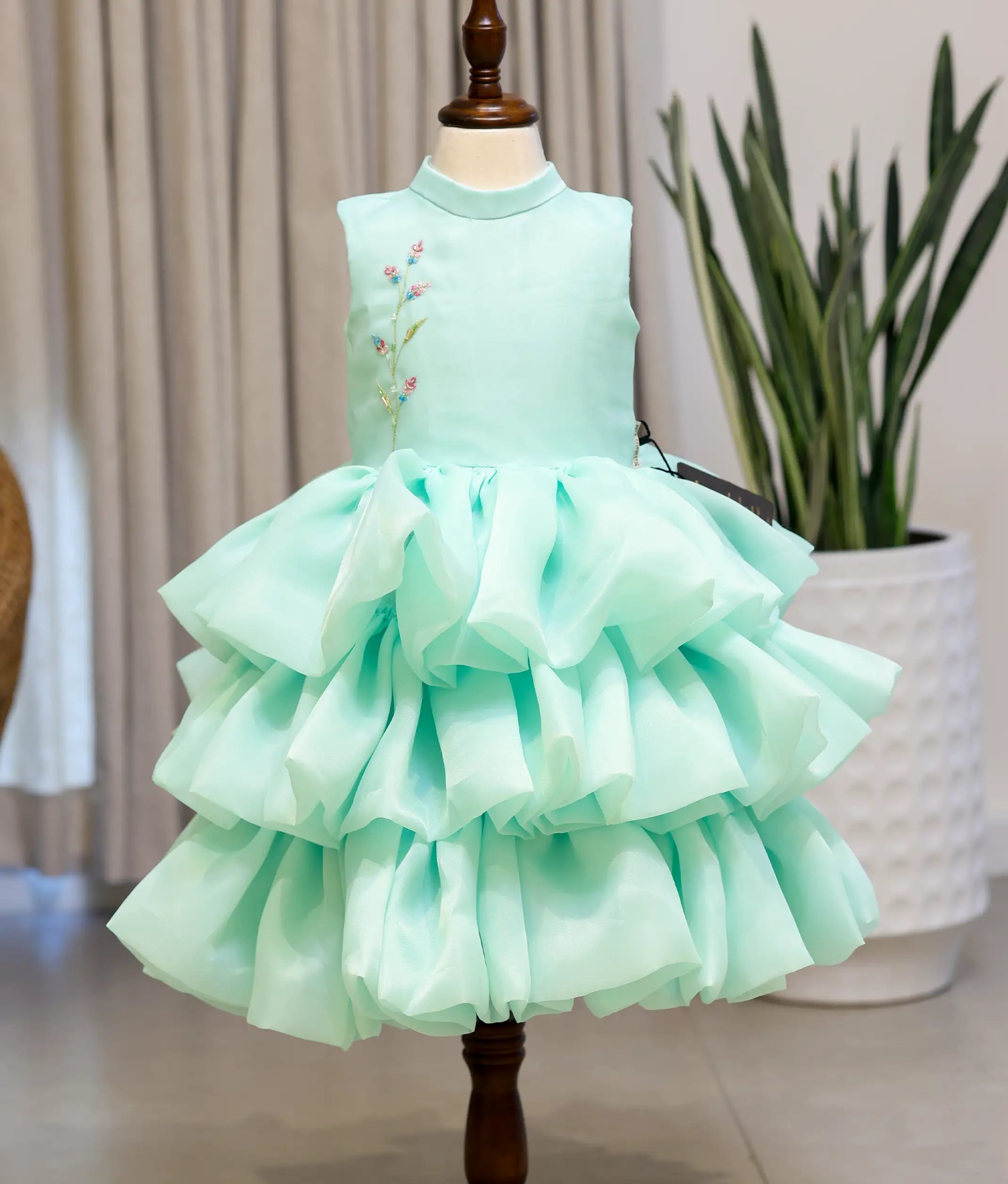 Front view of a pastel green organza step birthday dress for baby girls featuring floral handwork on the yoke and a triple-tiered voluminous skirt