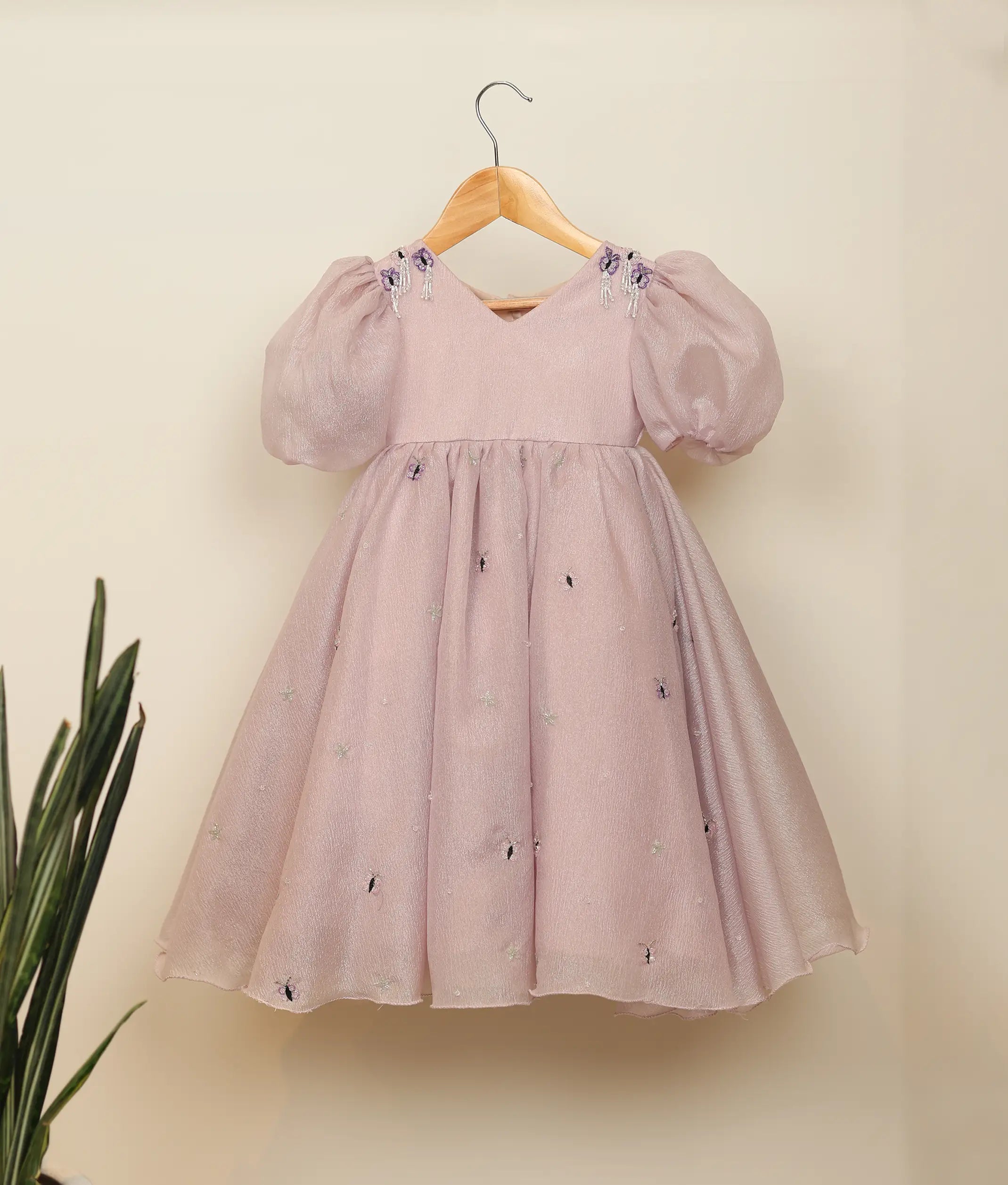 Front view of a pastel lavender crush organza birthday gown for baby girls with butterfly handwork and puff sleeves