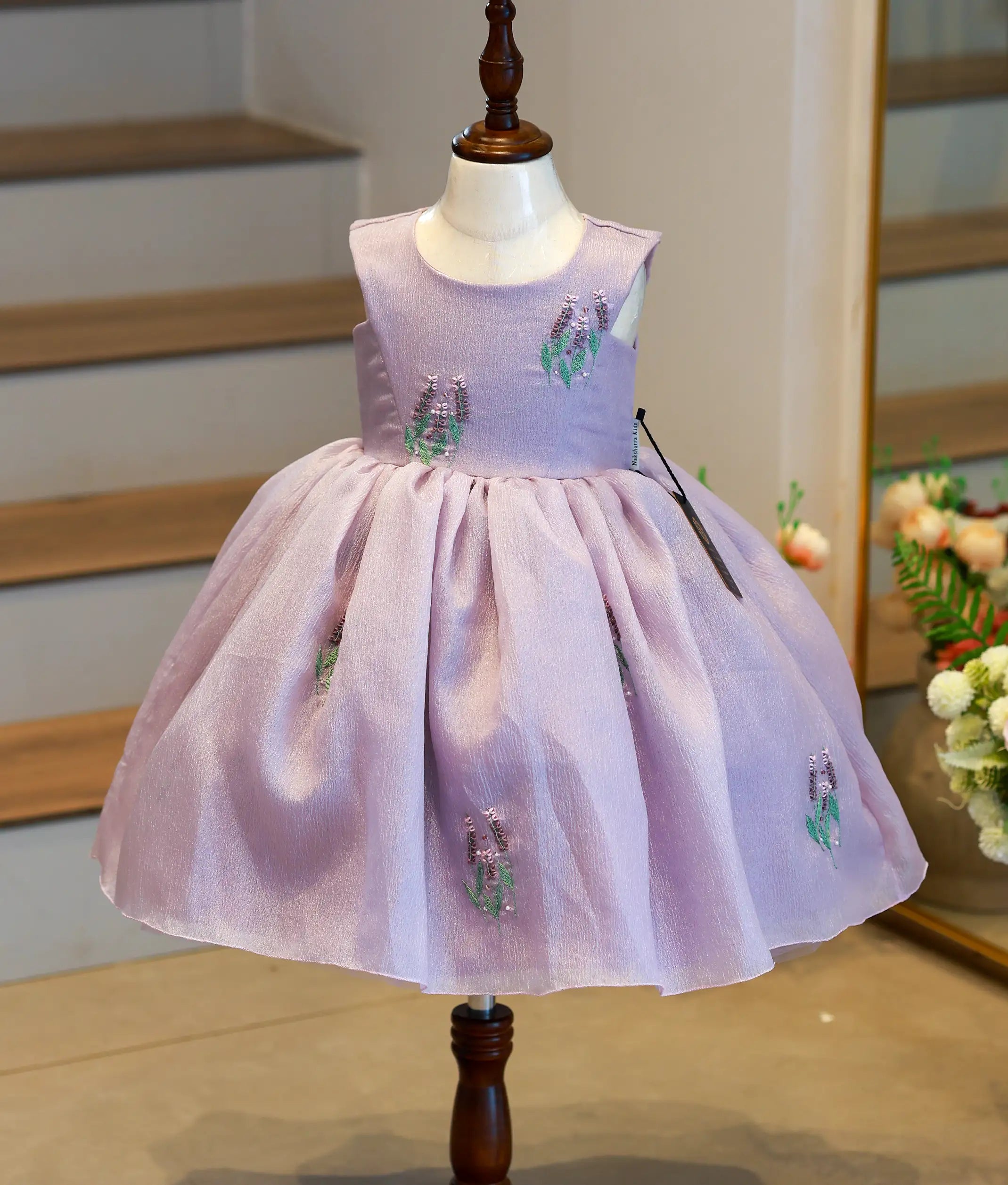 Front view of a pastel lavender crush organza birthday frock for baby girls featuring a floral handworked yoke and embroidered skirt