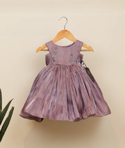 Front view of a pastel lavender laser organza birthday frock for baby girls featuring a floral handworked yoke and gathered flared skirt