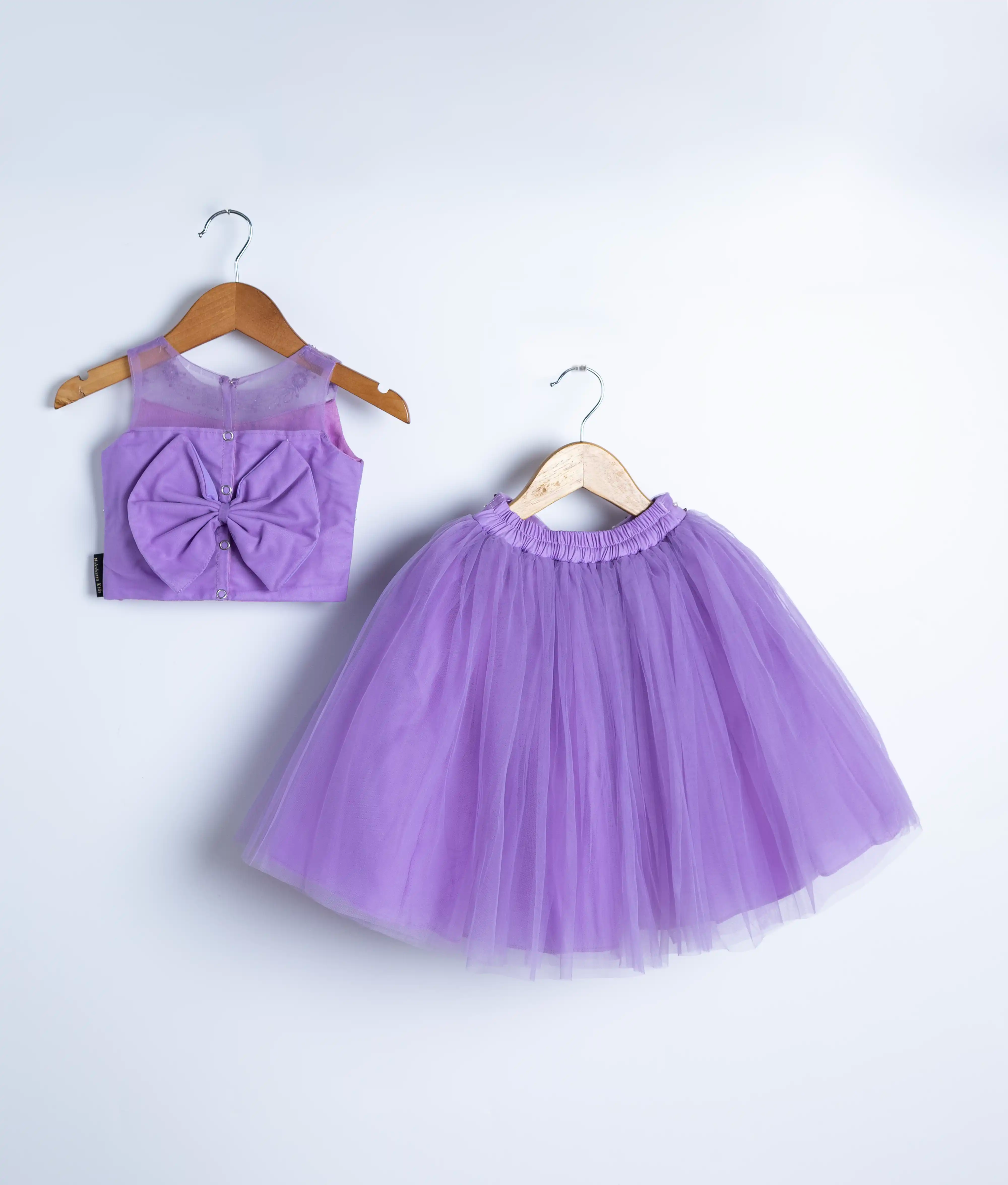 Flat lay of lavender baby girl outfit with floral applique top and matching tulle skirt
