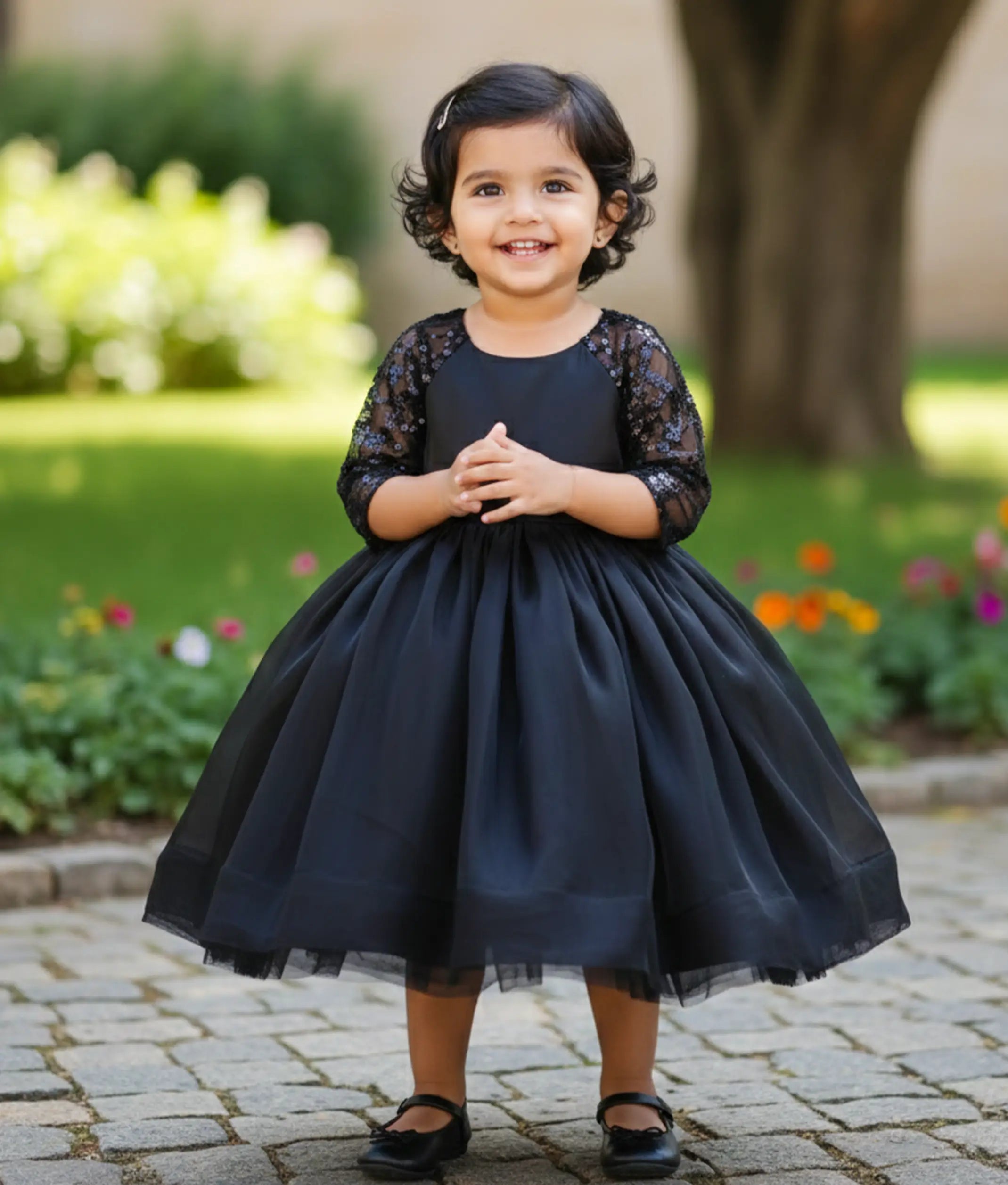Baby girl wearing a black lacer organza flower girl dress for baby girls featuring sheer embellished medium sleeves and a flared skirt