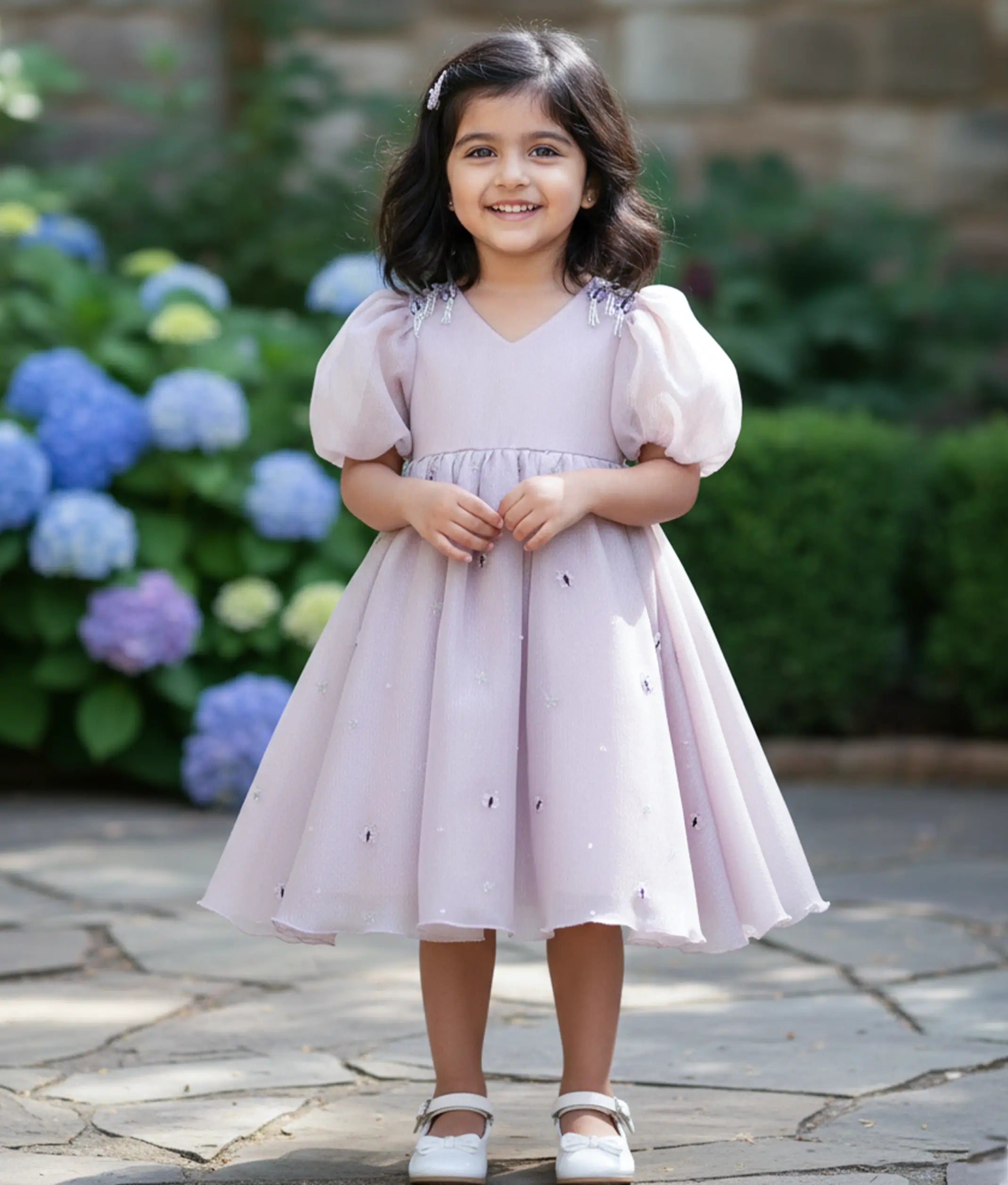 Baby girl wearing a pastel lavender crush organza birthday gown for baby girls with butterfly handwork and puff sleeves