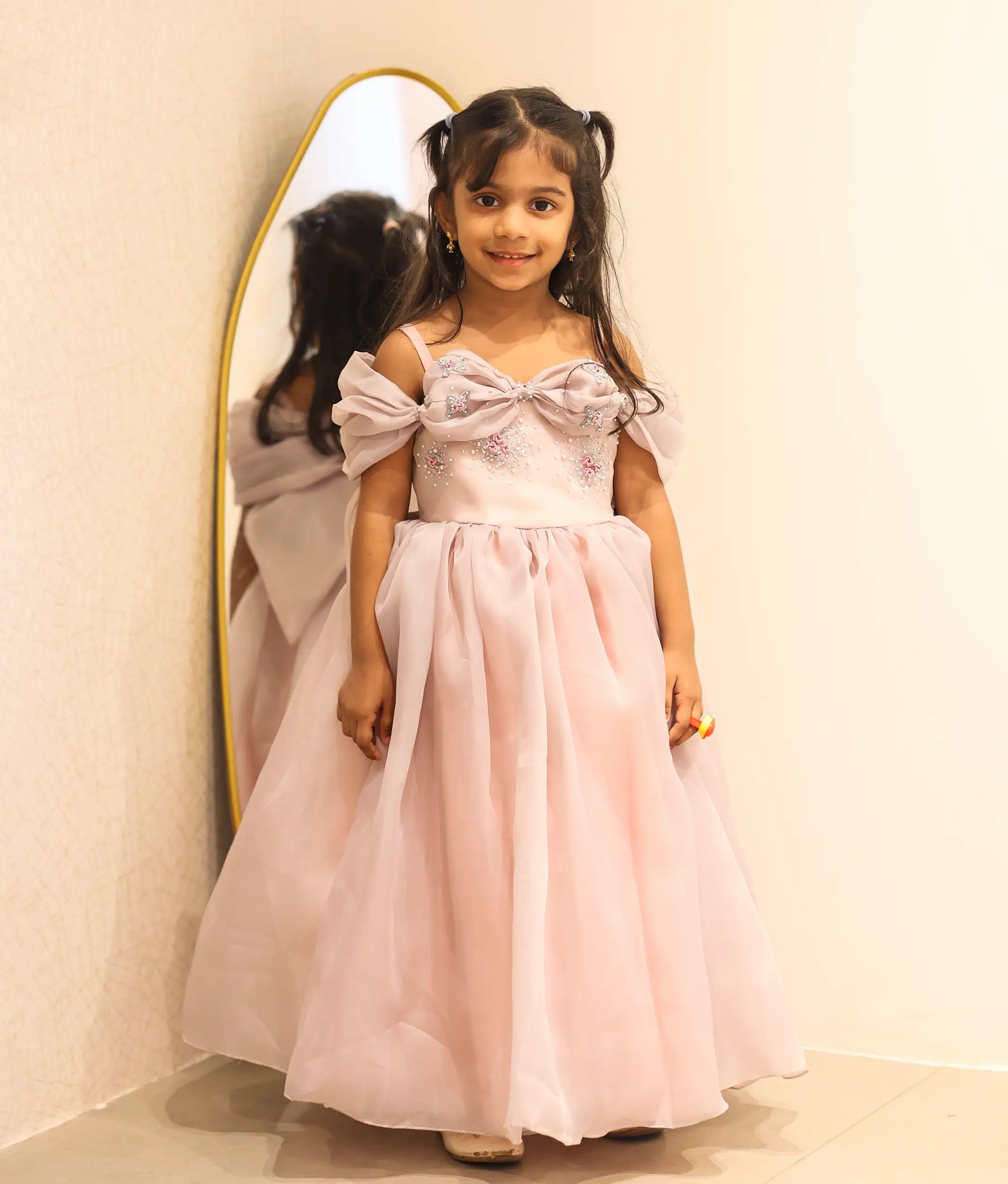 Baby girl wearing a pastel pink plain organza handworked birthday gown for baby girls featuring an off-the-shoulder bodice and full-length skirt