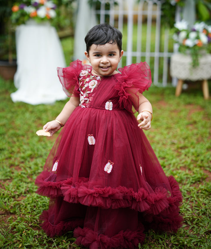 Baby girl wearing maroon handworked butterfly theme birthday gown