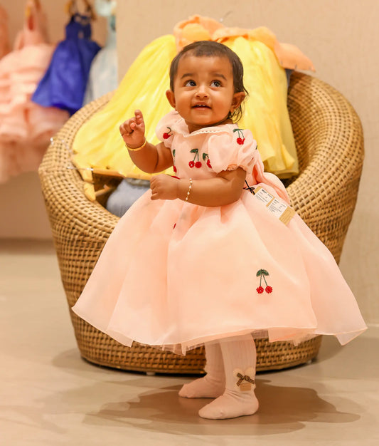 Baby girl wearing pastel peach plain organza cherry theme dress