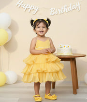 Baby girl wearing a vibrant yellow laser organza birthday dress for baby girls featuring spaghetti straps and a multi-layered step skirt