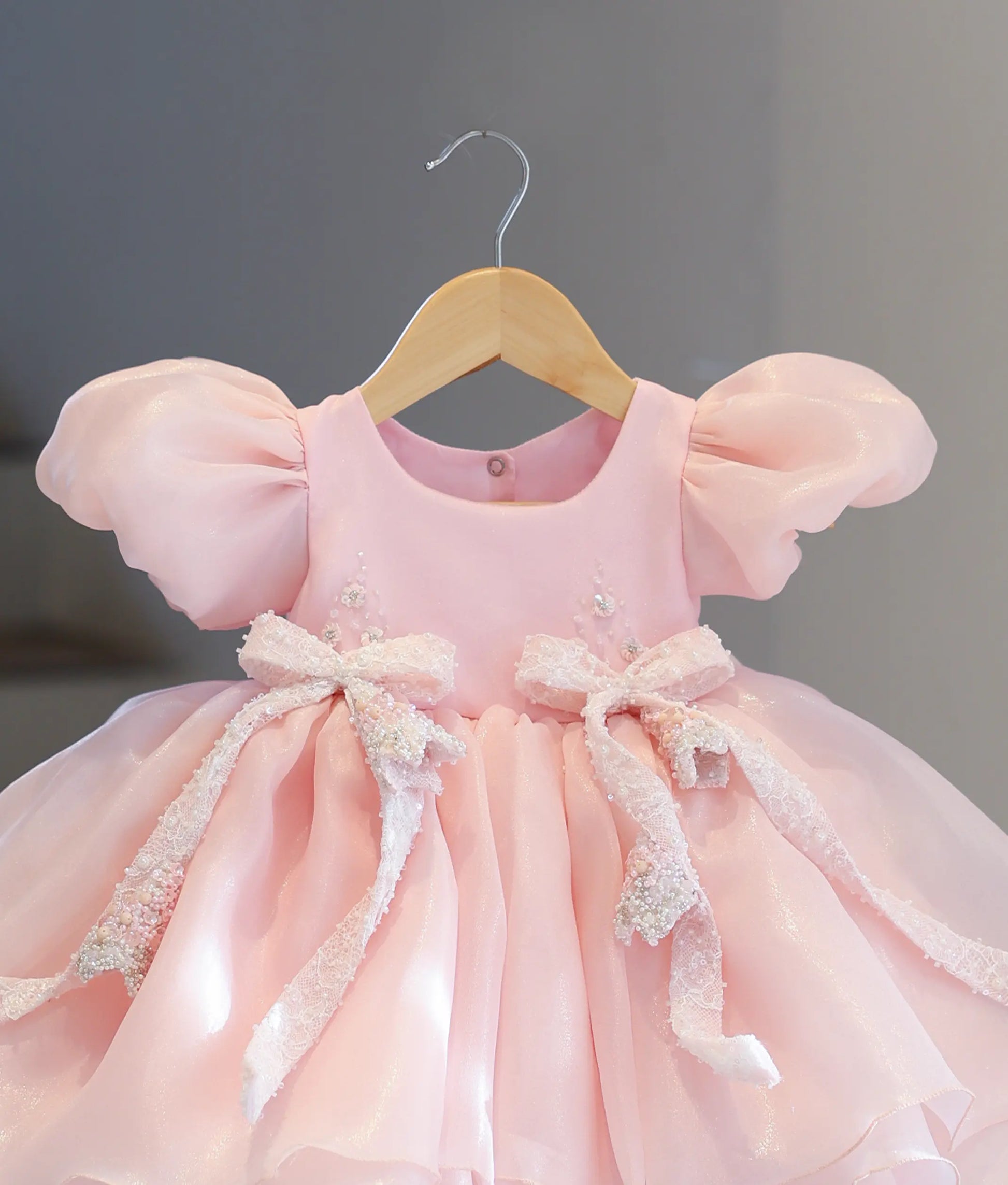 Close-up of the delicate floral handwork with sequins, beads, and two hand-beaded lace bows on the top bodice of the baby pink shimmer organza frock.