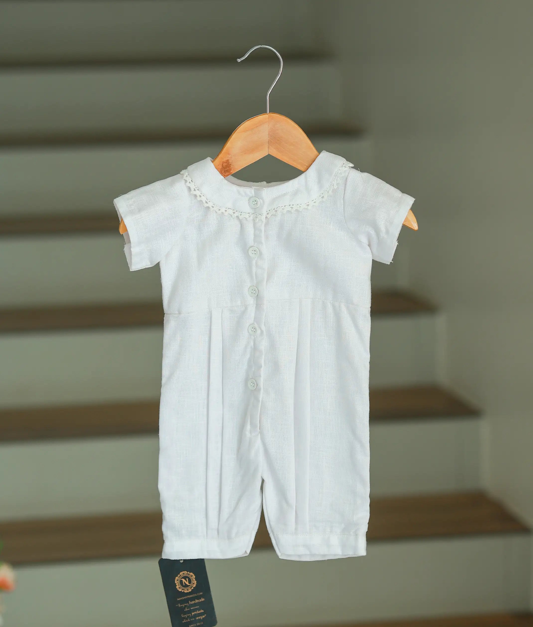 The back view of the white cotton romper showing the full-length white button closure and clean finish