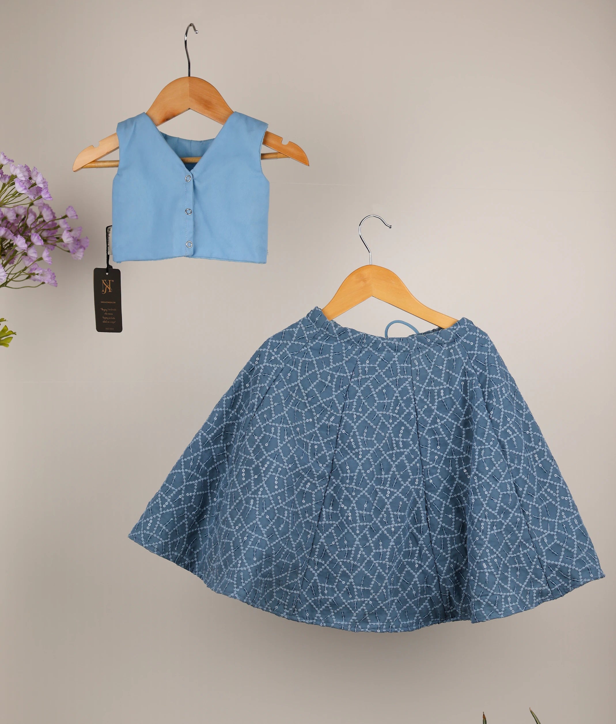 Back view showing the V-neckline with press button closure on the blue top and the flared ash georgette skirt