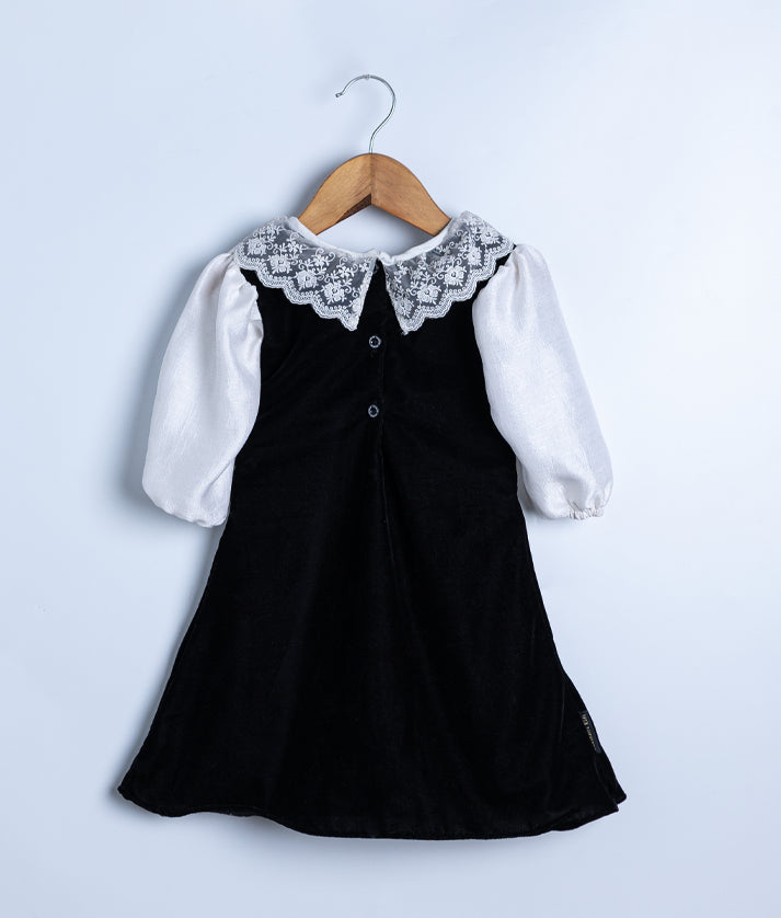 Back view of the black velvet frock, showing the round neck closure with a press button and the smooth velvet fabric.