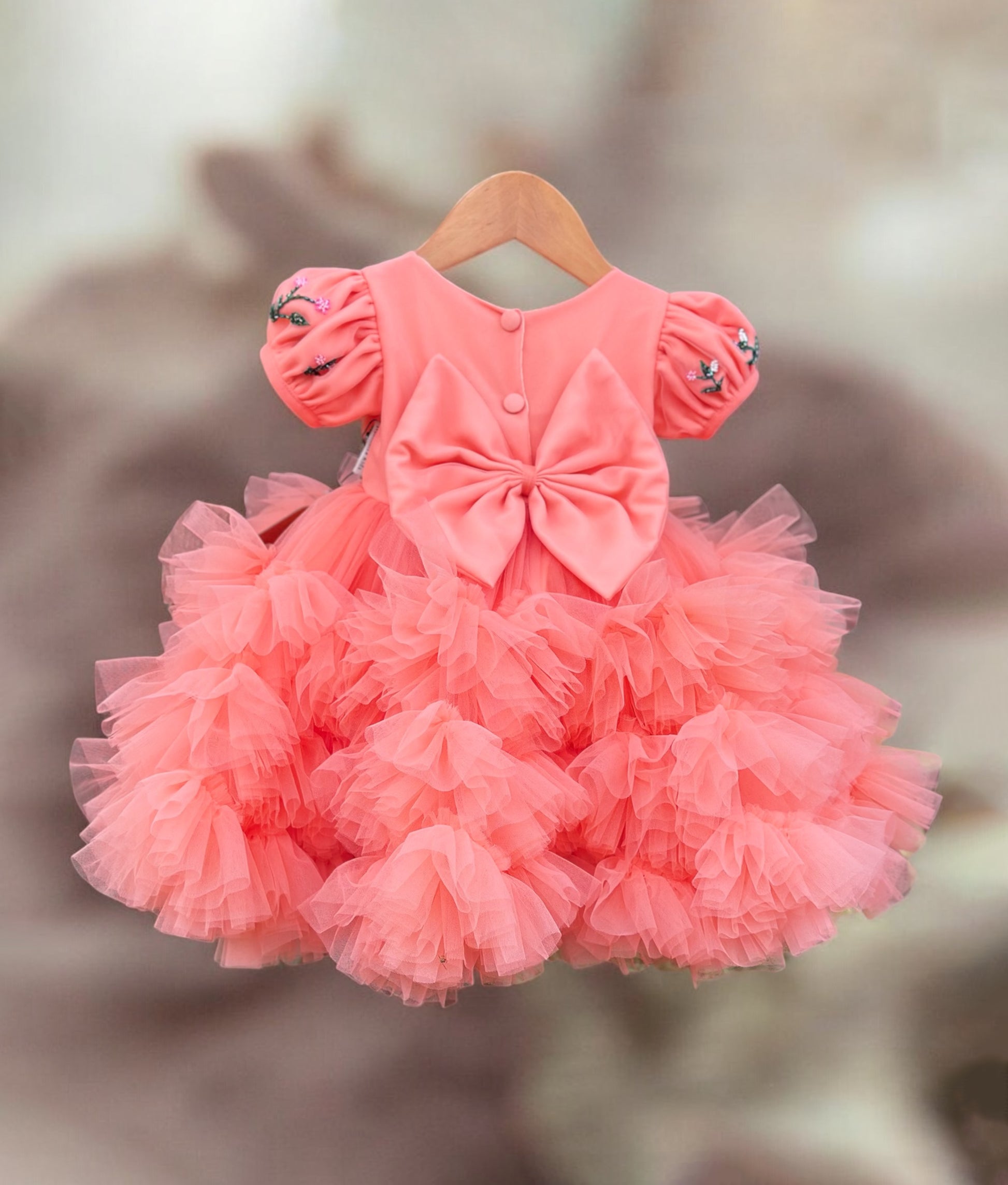 Back view of coral baby girl frock with big bow and fluffy ruffle layers – ideal for party wear