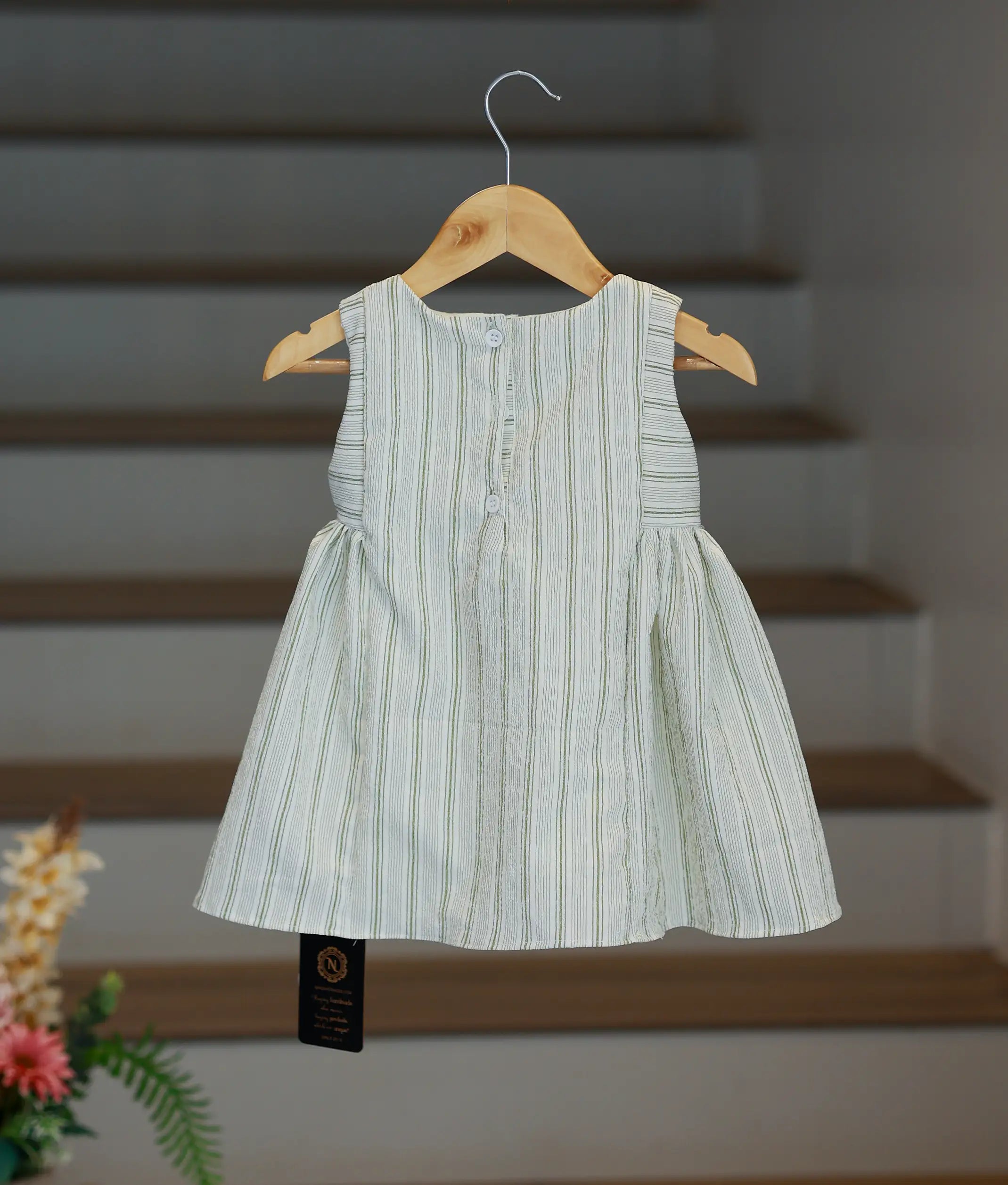 The back view of the striped frock showing the button-down closure and pleated skirt design