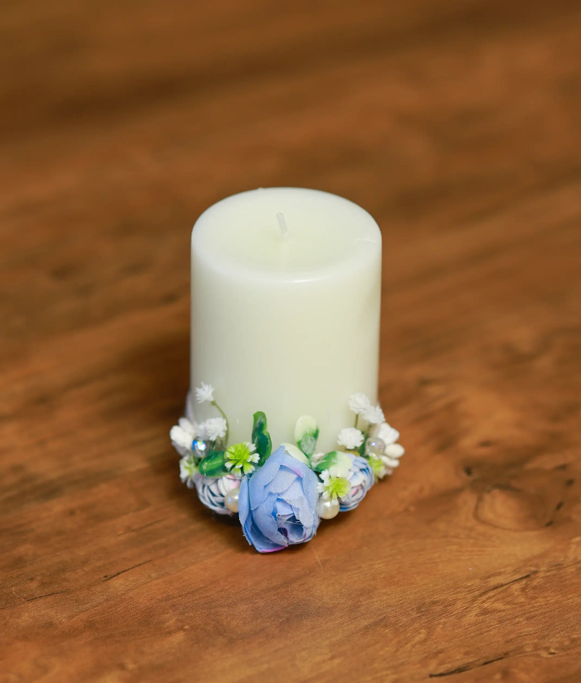 Close-up of the baptism candle floral detail featuring a sky blue rose, white pearls, and shimmering crystals