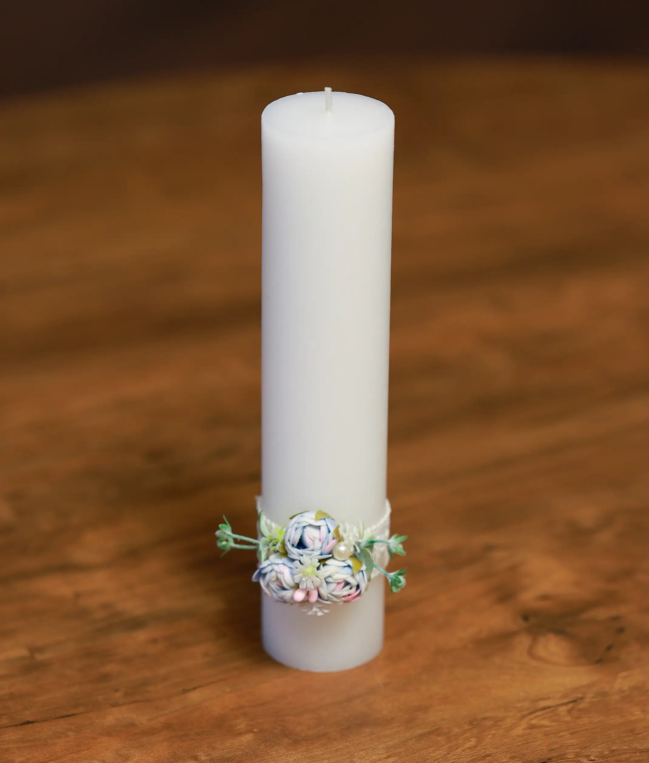 Close-up of the baptism candle showing the handmade blue and pink flowers, white pearl, and lace detailing