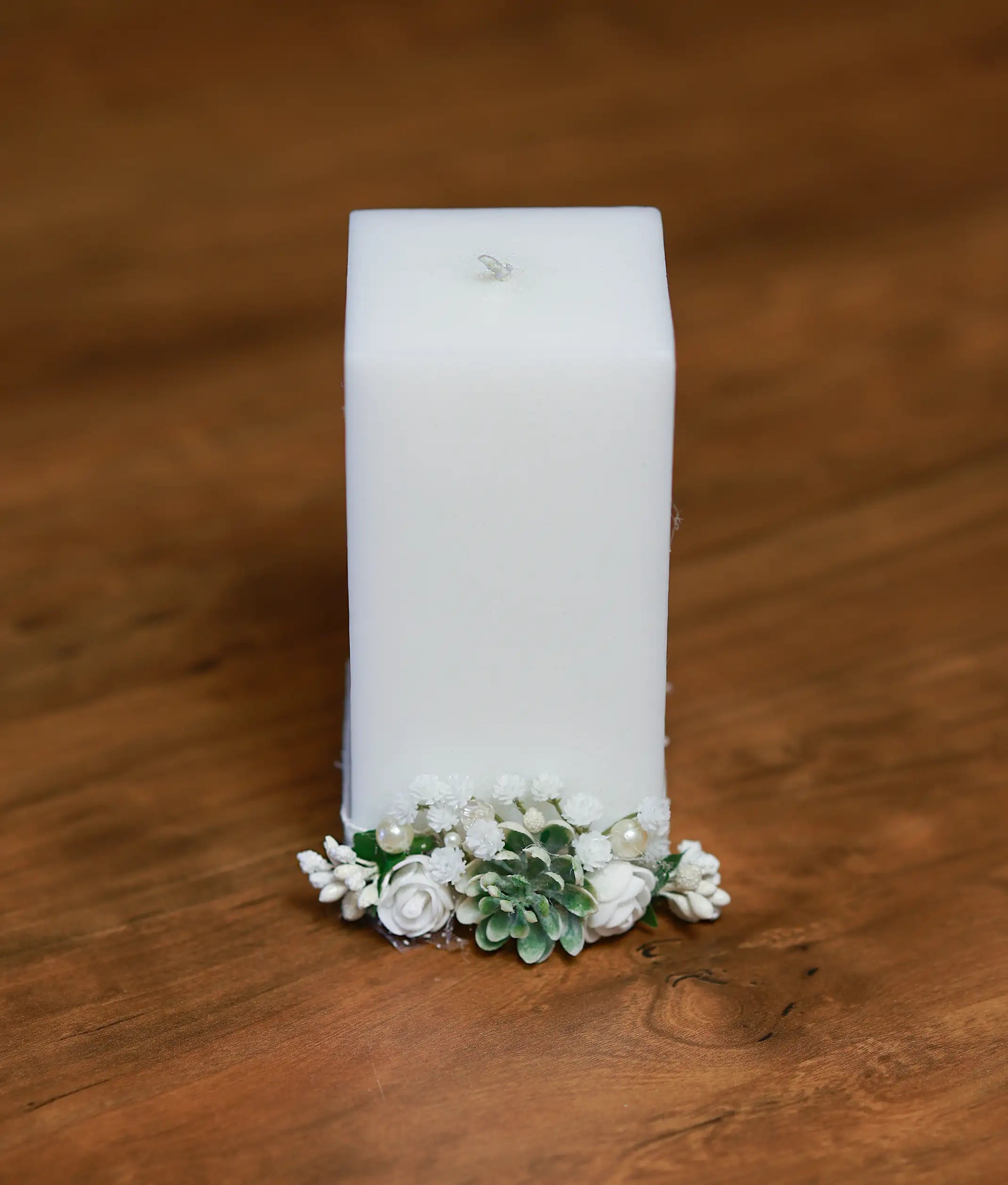 Close-up of the handcrafted white flowers, green leaf accents, and shimmering pearls on the baptism candle