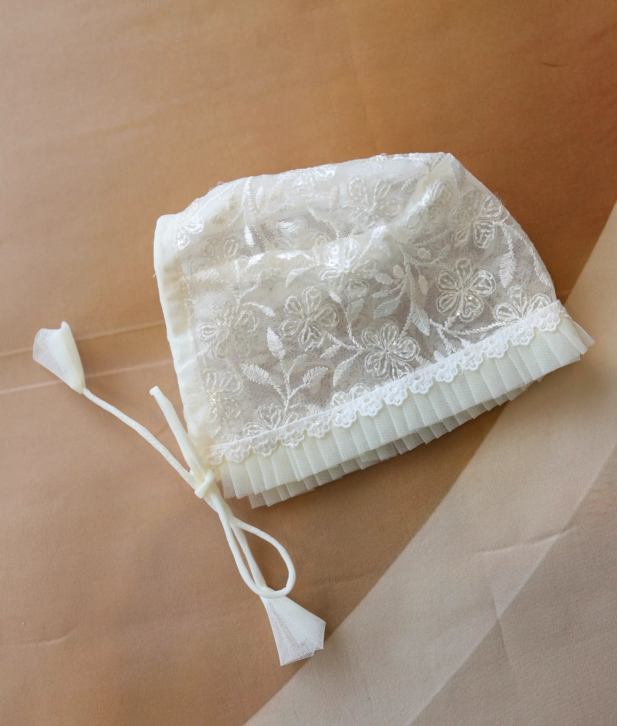 Close-up showing the intricate floral embroidery and smooth edge of the baptism cap.