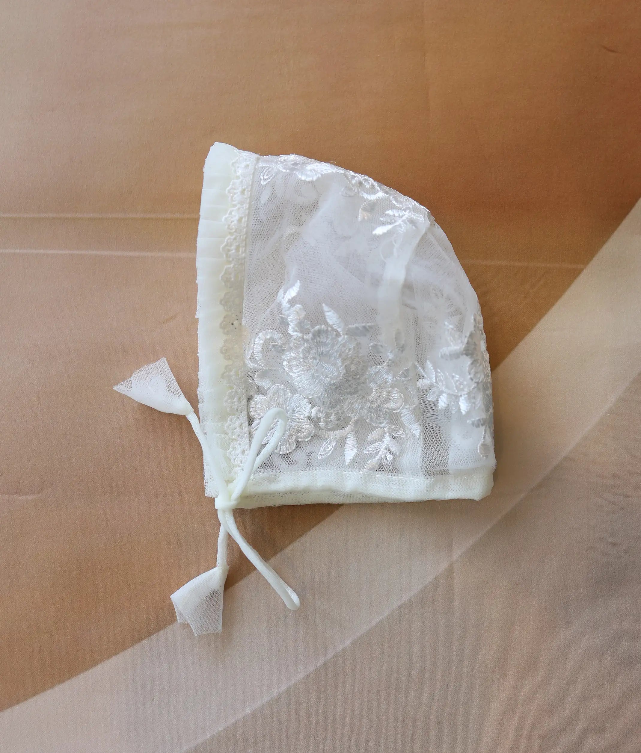 Close-up showing the intricate floral embroidery and smooth edge of the baptism cap.