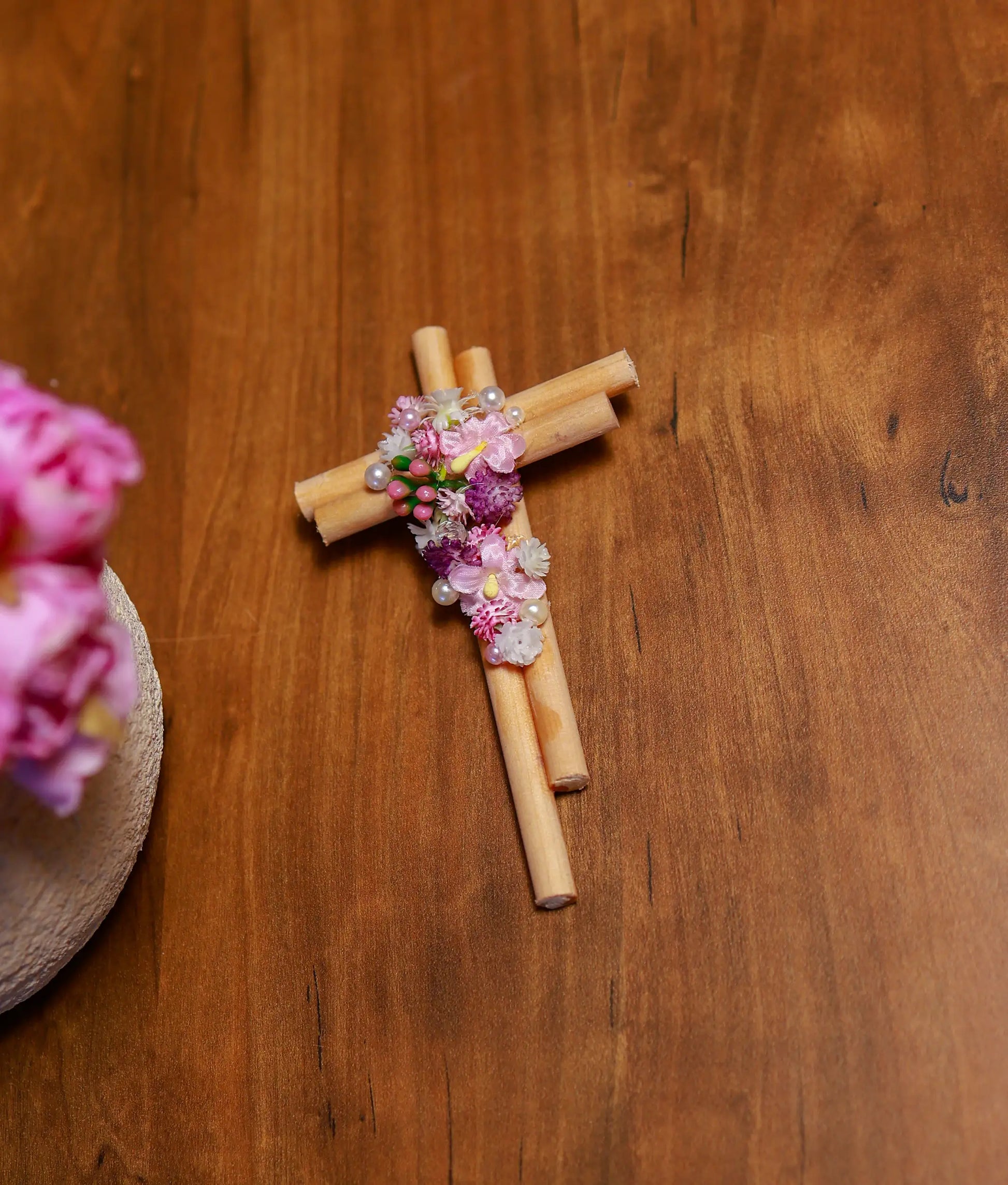 Close-up view of the pink paper flowers, white pearls, and shimmering granules on the baptism cross