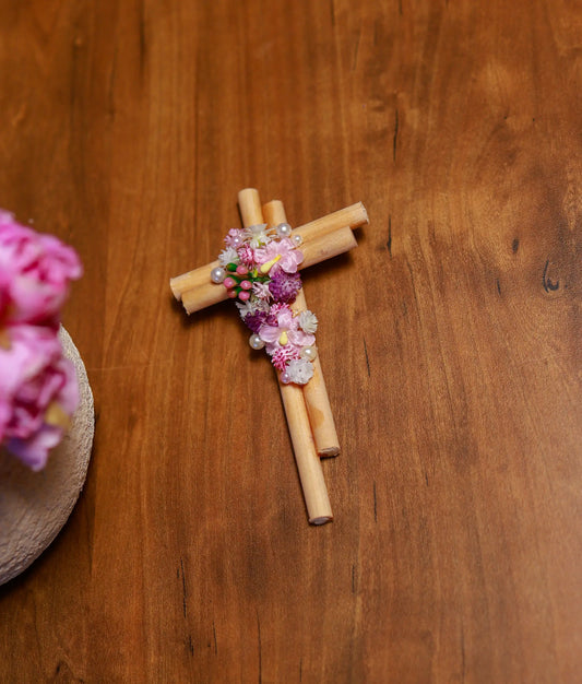Close-up view of the pink paper flowers, white pearls, and shimmering granules on the baptism cross