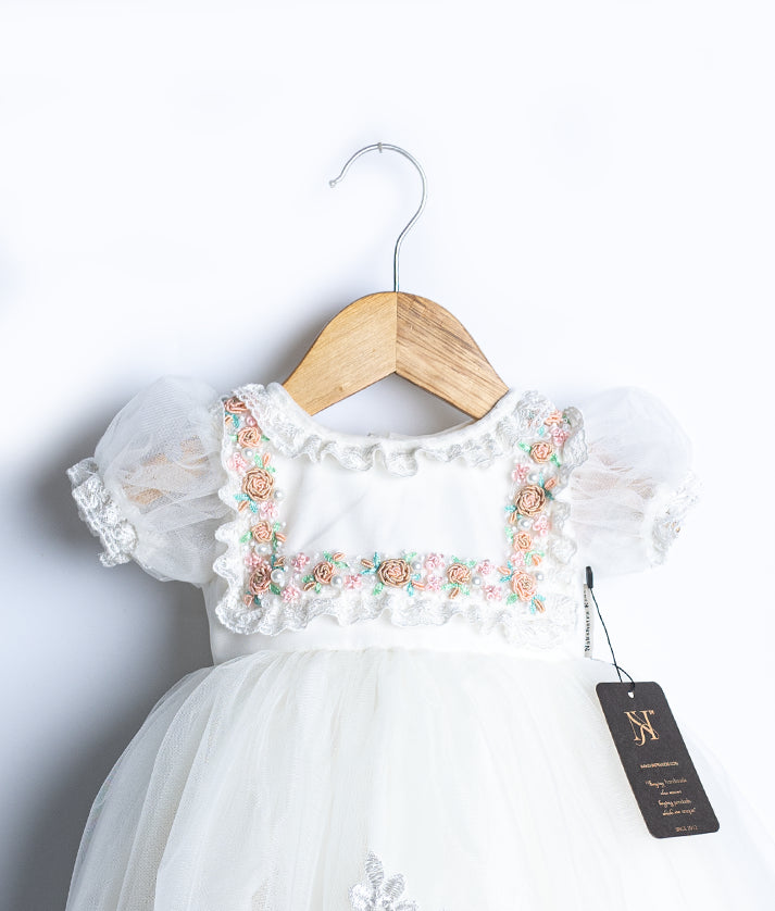 Close-up of exquisite pearl handwork and delicate lace on a designer off-white christening frock for babies