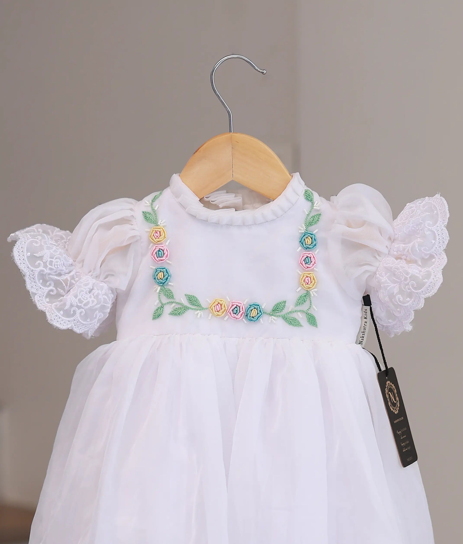 Close-up of intricate hand-stitched pearls and delicate lace detailing on a designer boutique baptism frock for infants.