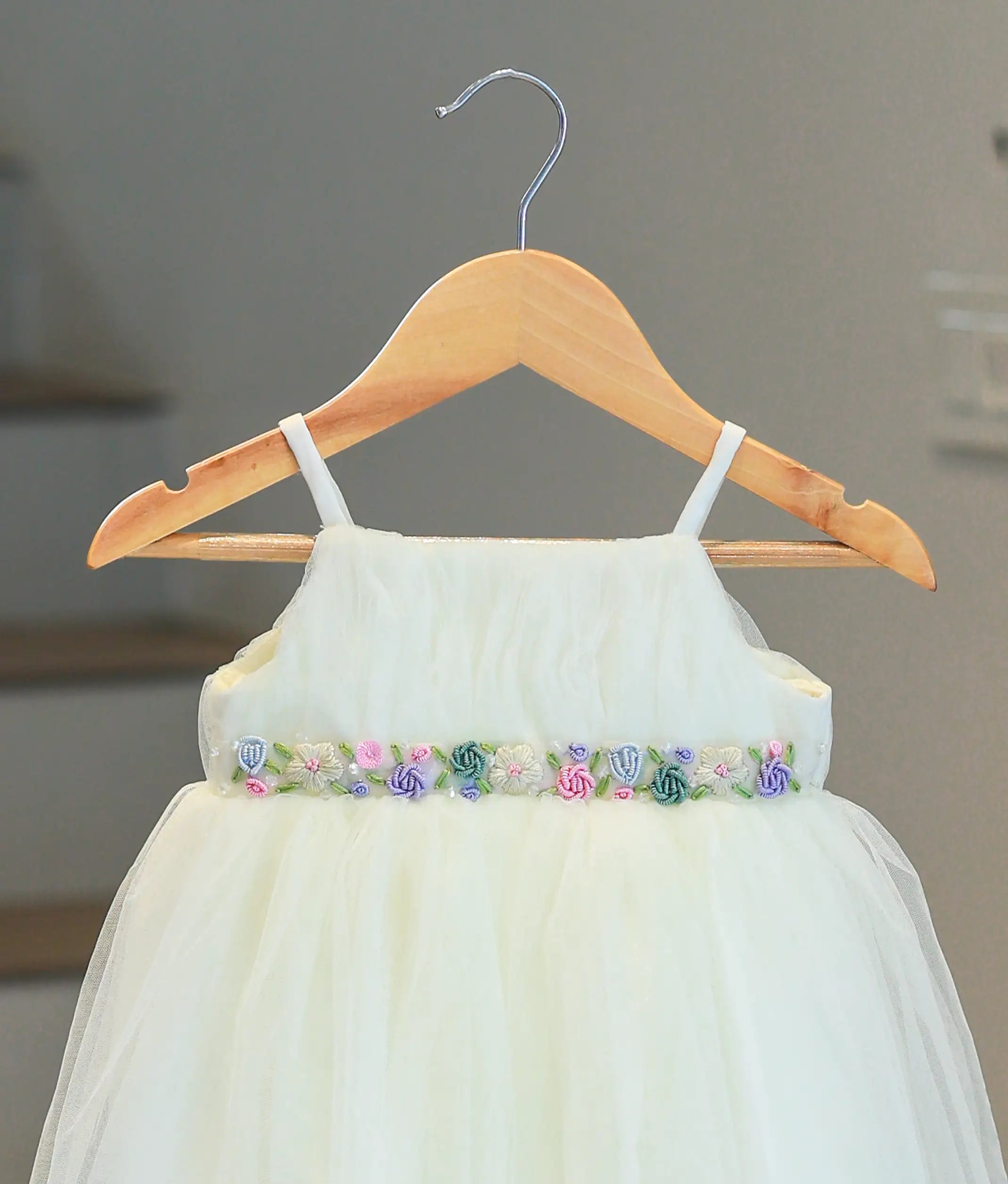 Close-up of the multicolored floral hand embroidery and beadwork at the waistline of the baptism gown.