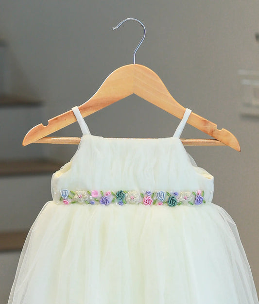 Close-up of the multicolored floral hand embroidery and beadwork at the waistline of the baptism gown.