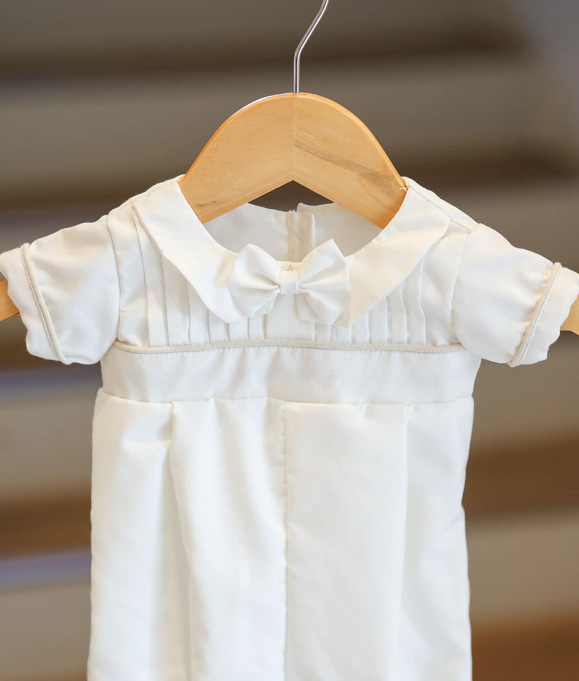 Close-up of the cream piping on the waist and sleeves of the white romper.