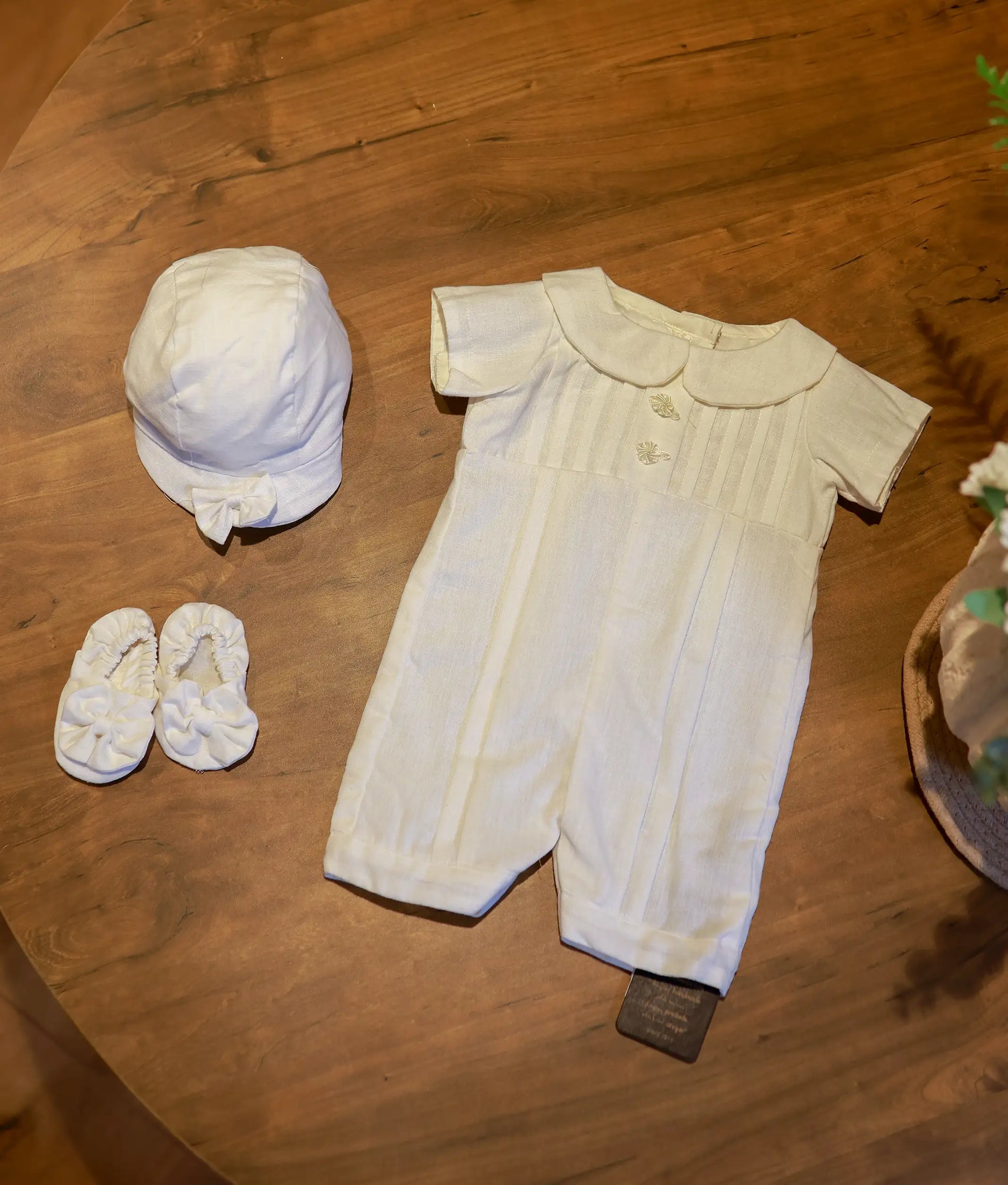 Complete 3-piece baptism set for baby boys including the pleated romper, a matching bow cap, and soft fabric booties