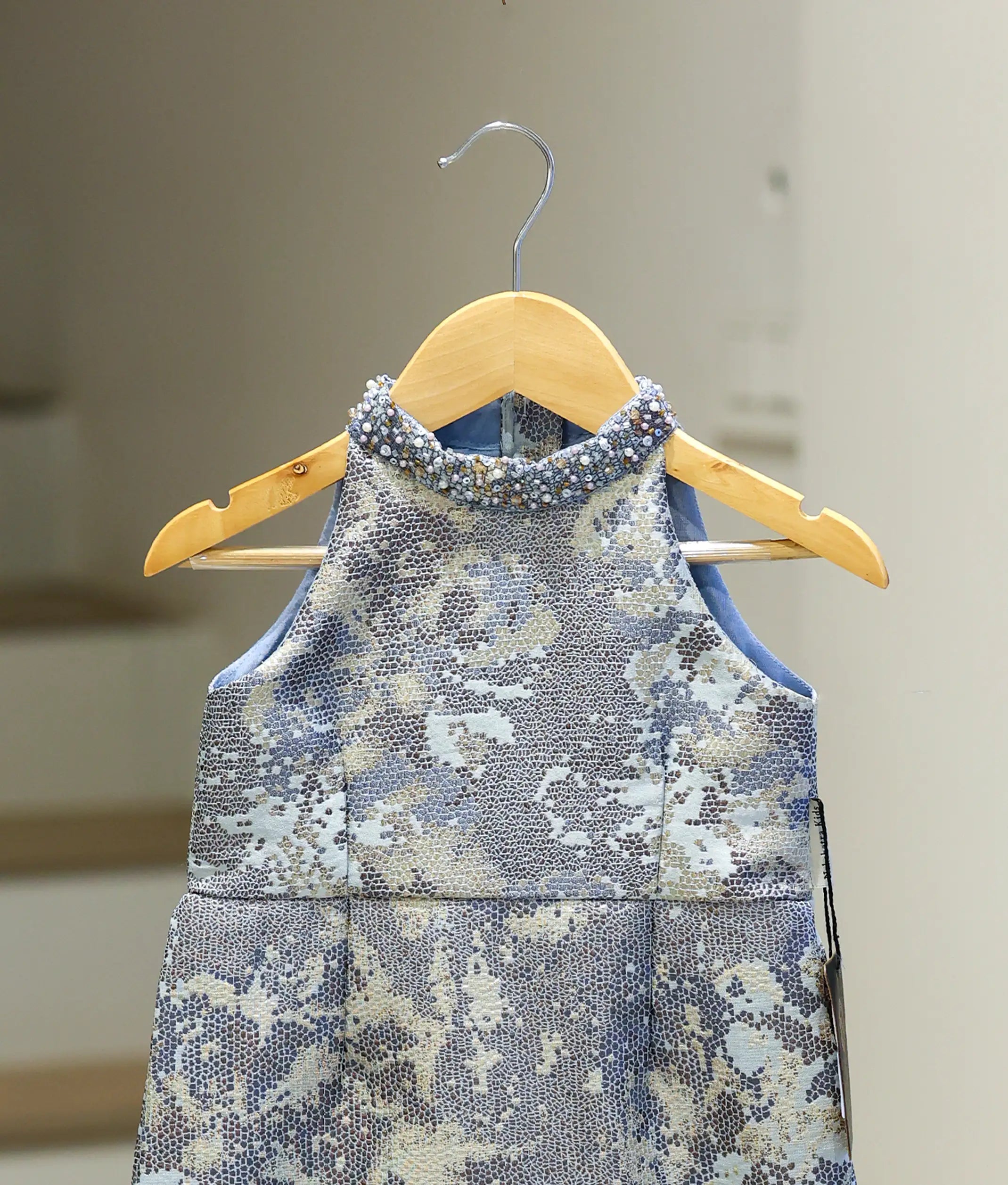 Close-up of the hand-worked bead detailing on the halter neck and the textured jacquard pattern.