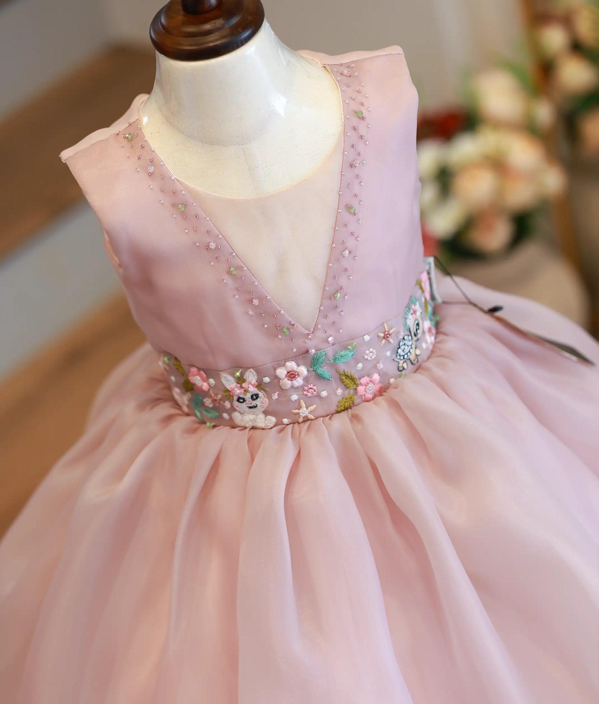 Close-up of the beige bodice showing the bead-adorned neckline and whimsical animal-themed cartoon embroidery at the waist