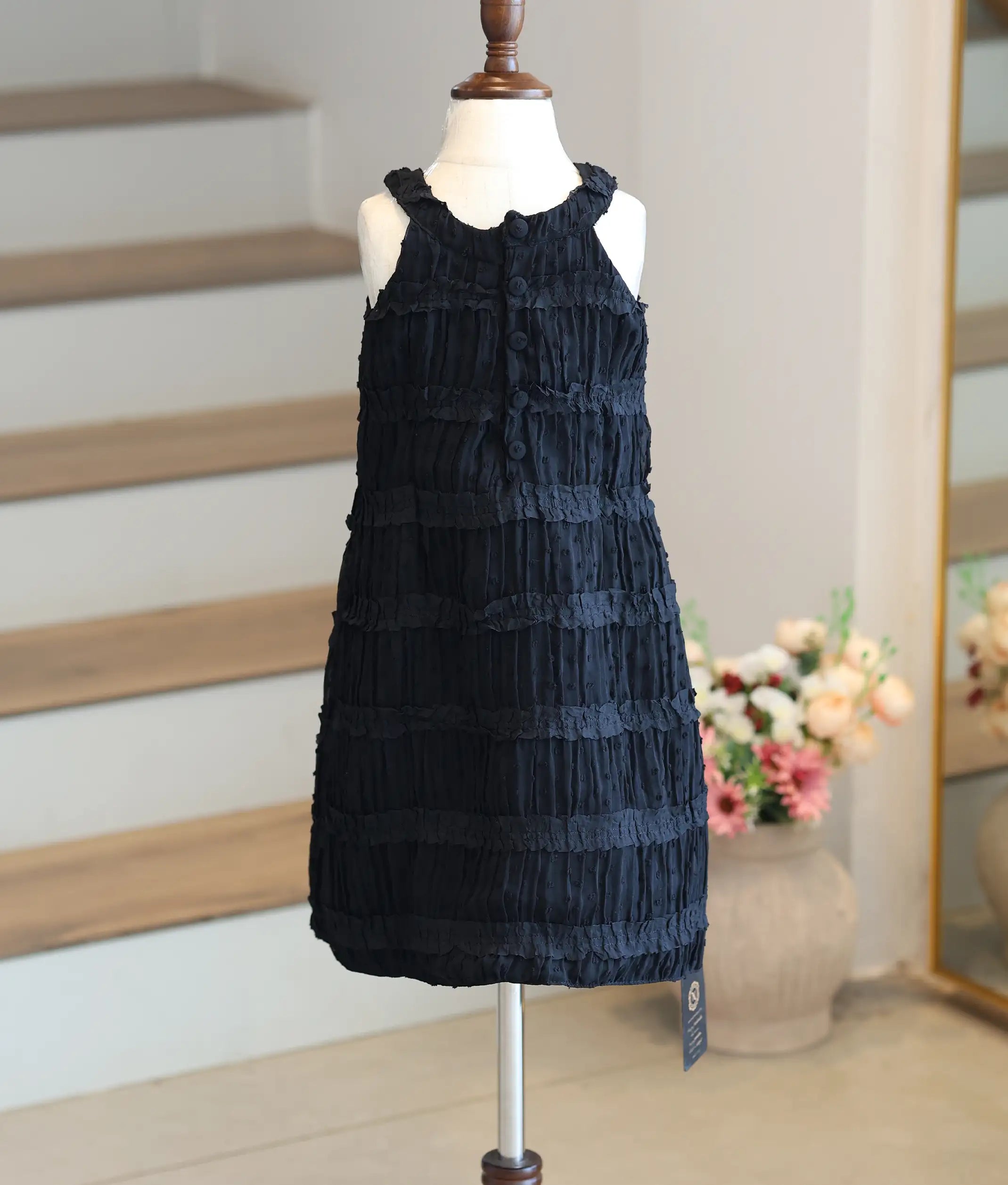 Back view of the black A-line frock highlighting the halter back and button closure.