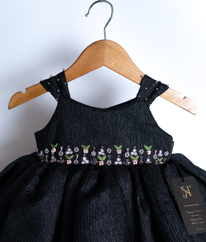 Close-up of the black frock yoke showing the hand-embroidered floral design and tiny gems on the wide straps