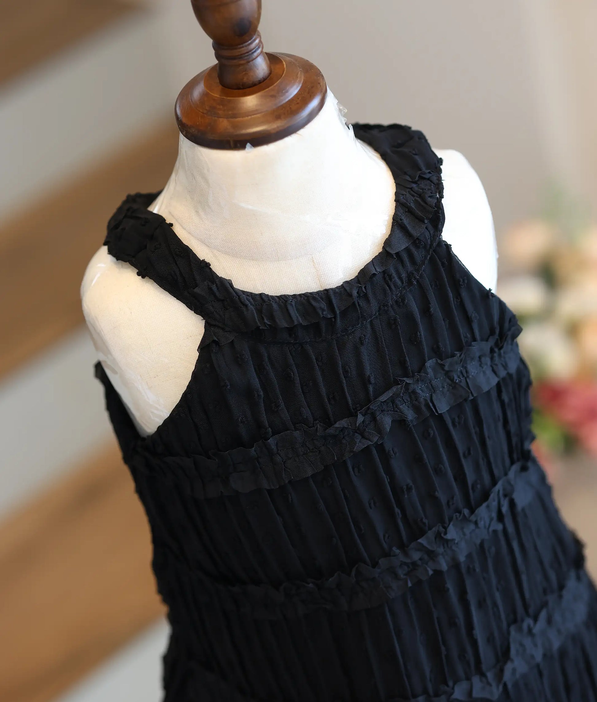 Close-up of the horizontal ruffled tiers and halter neck design on the black textured frock.