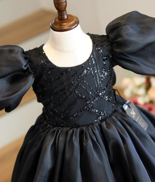 Close-up of the sparkling sequin appliqué and crystal-highlighted back bow on the black organza party dress
