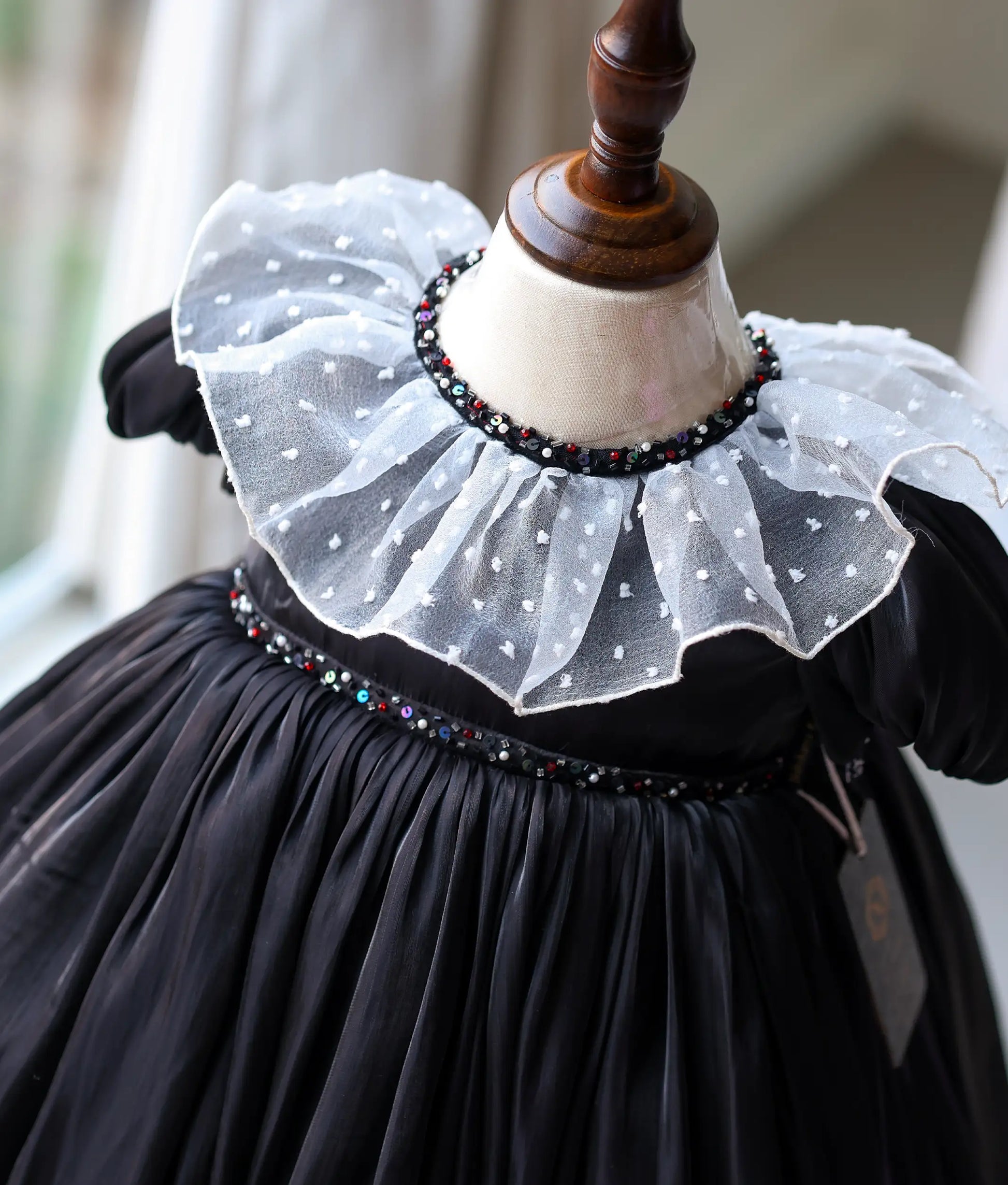 Close-up of black gown showing intricate pearl and crystal handwork on the neckline, waist, and short puff sleeves