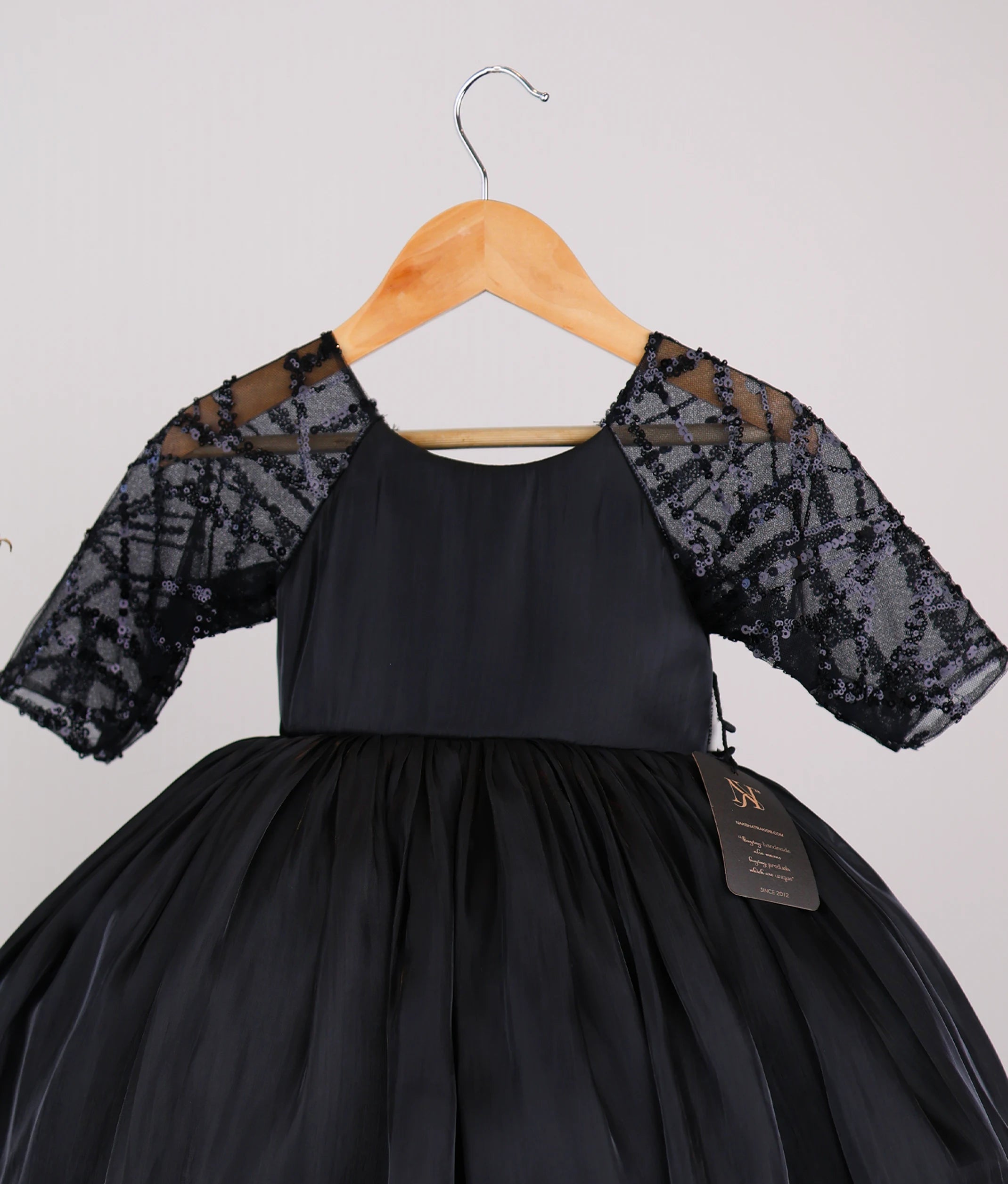Close-up of the delicate worked material on the sheer medium sleeves and the lacer organza yoke of the black flower girl dress