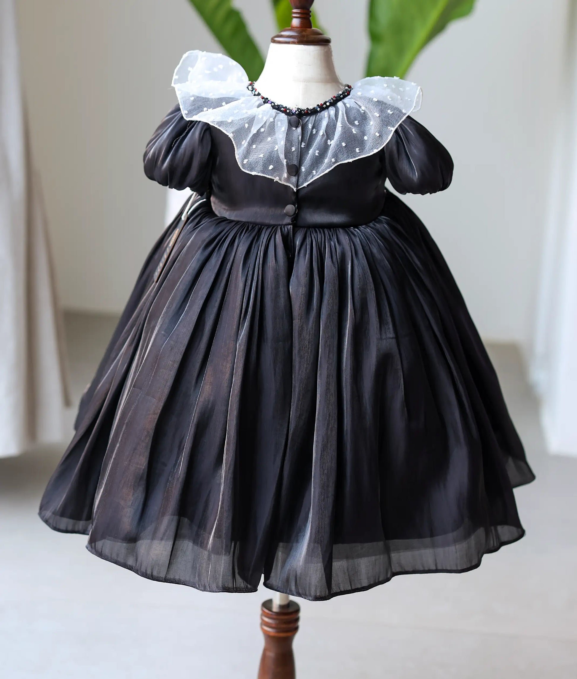 Back view of the black laser organza gown featuring a round neckline with decorative show buttons