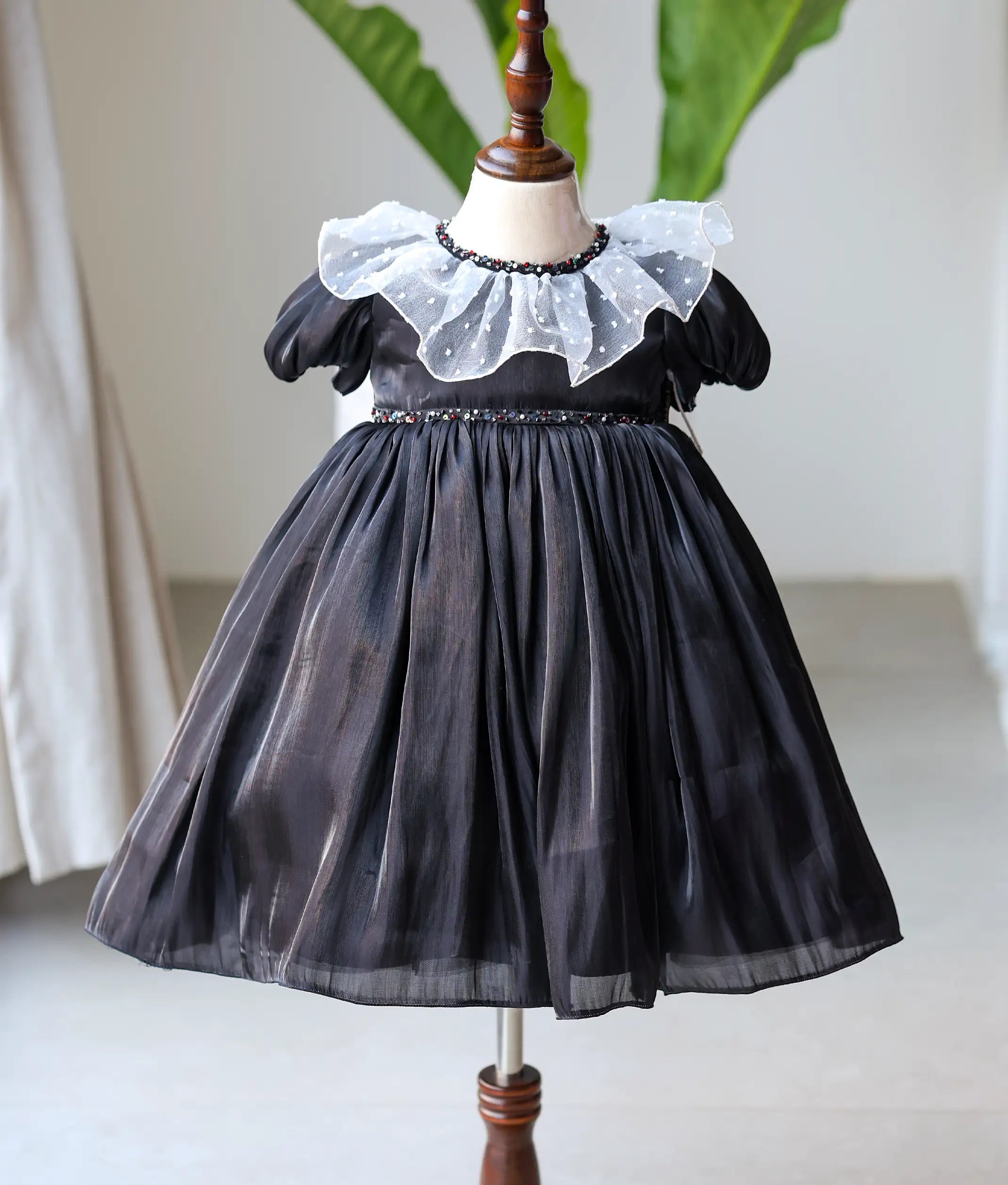 Front view of a black laser organza girls' birthday gown with pearl and crystal handwork and a full-length flared skirt