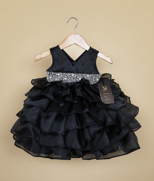 Front view of a black organza girl's birthday frock with pleated V-neck bodice and layered ruffle skirt