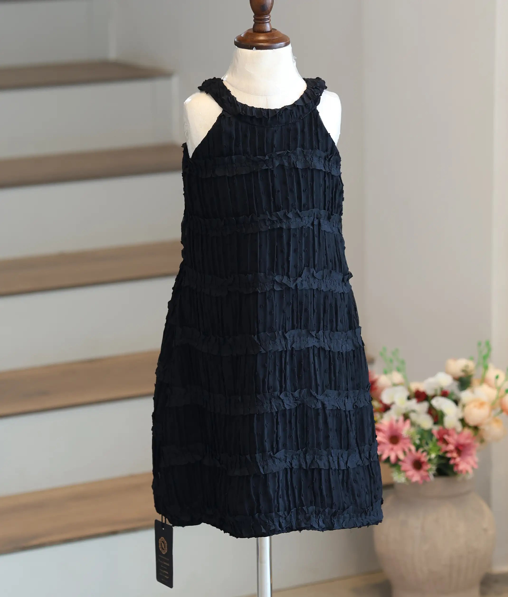 Front view of a black A-line birthday frock for baby girls featuring a tiered ruffle halter neck.