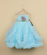 Blue frock for baby girl with multiple ruffle layers and full tulle skirt on wooden hanger