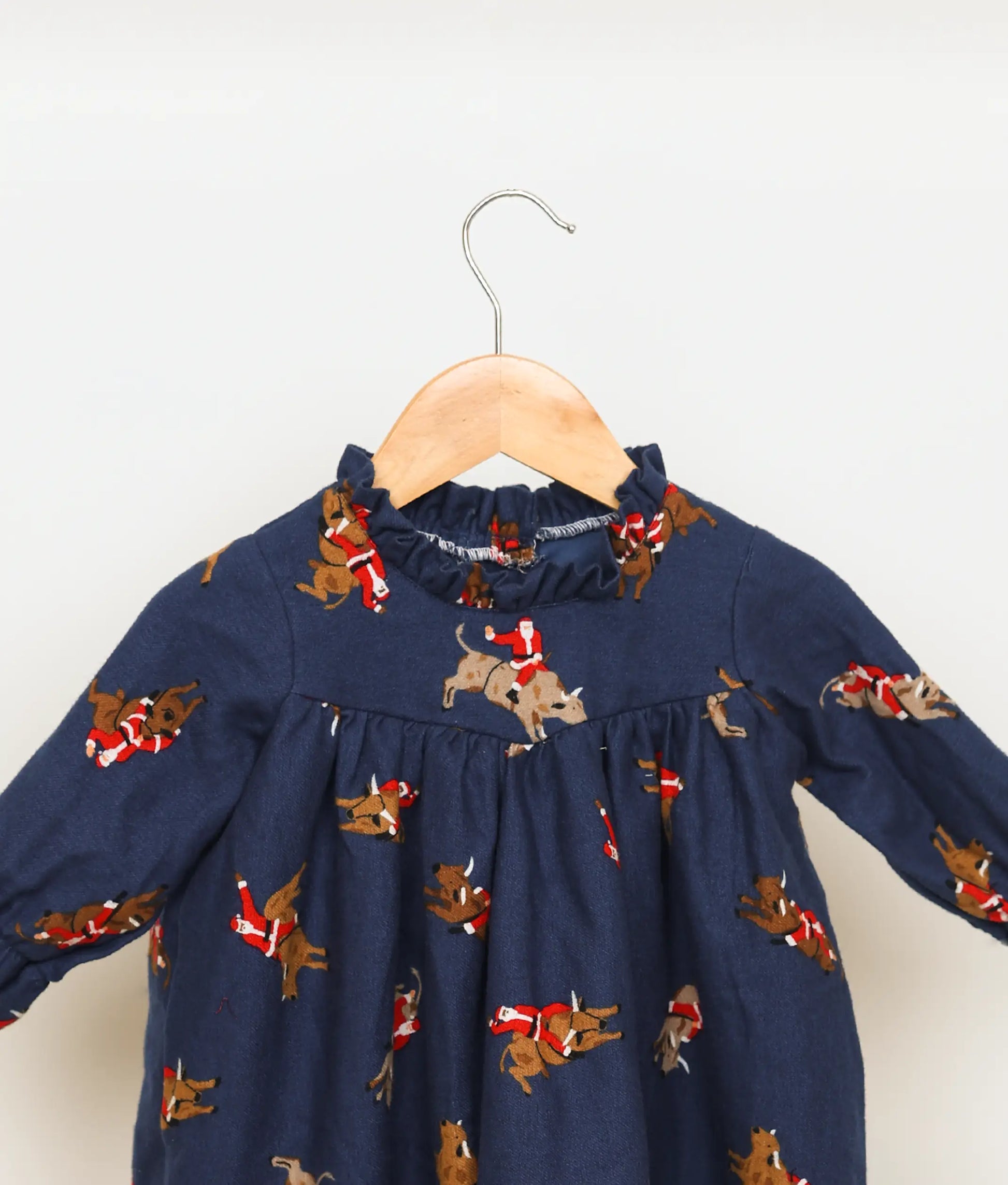 Close view of an Santa Claus printed yoke on the blue baby girl cotton Christmas frock.