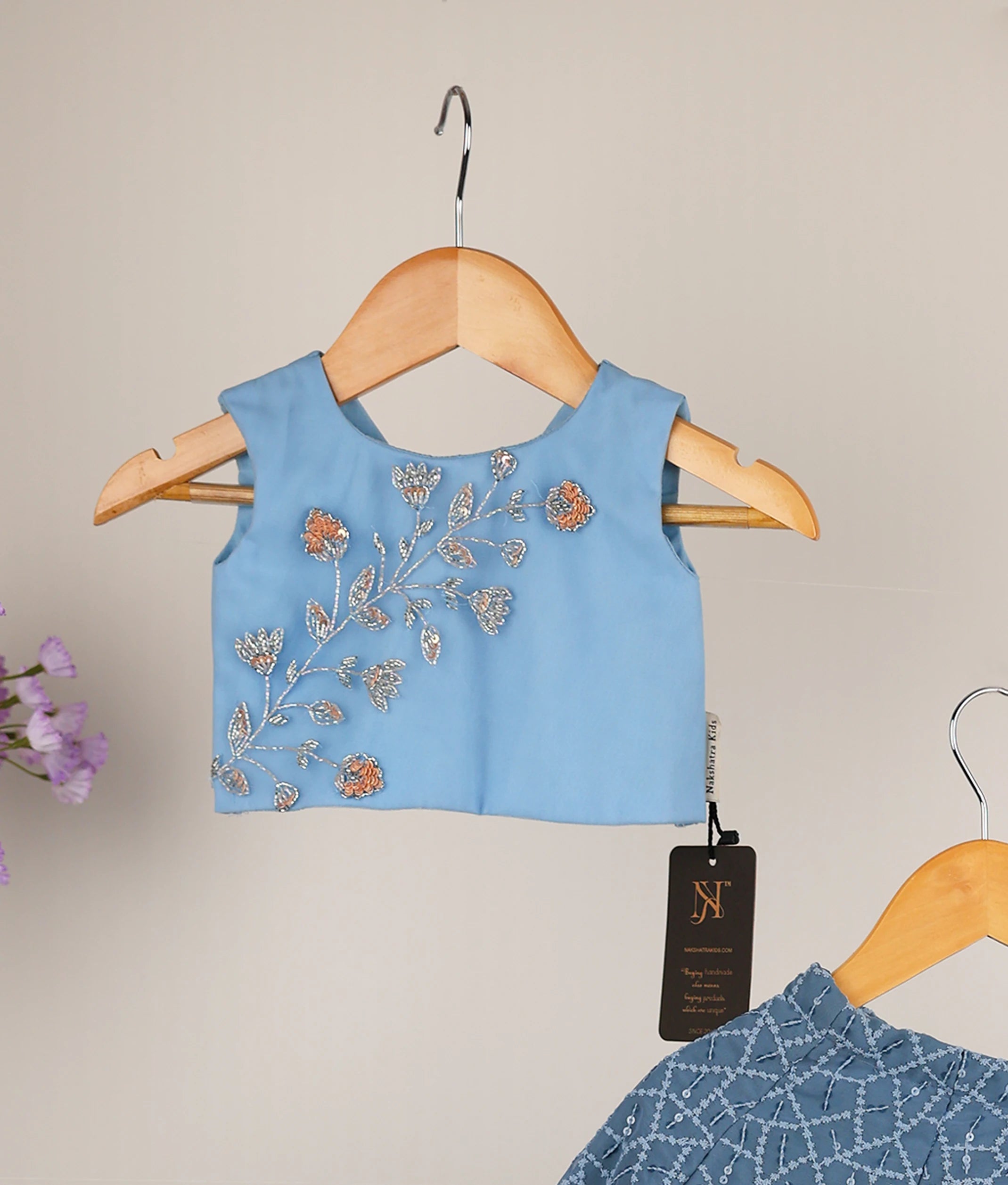 Close-up of blue tulle top featuring intricate silver and peach floral handwork and a classic round neckline