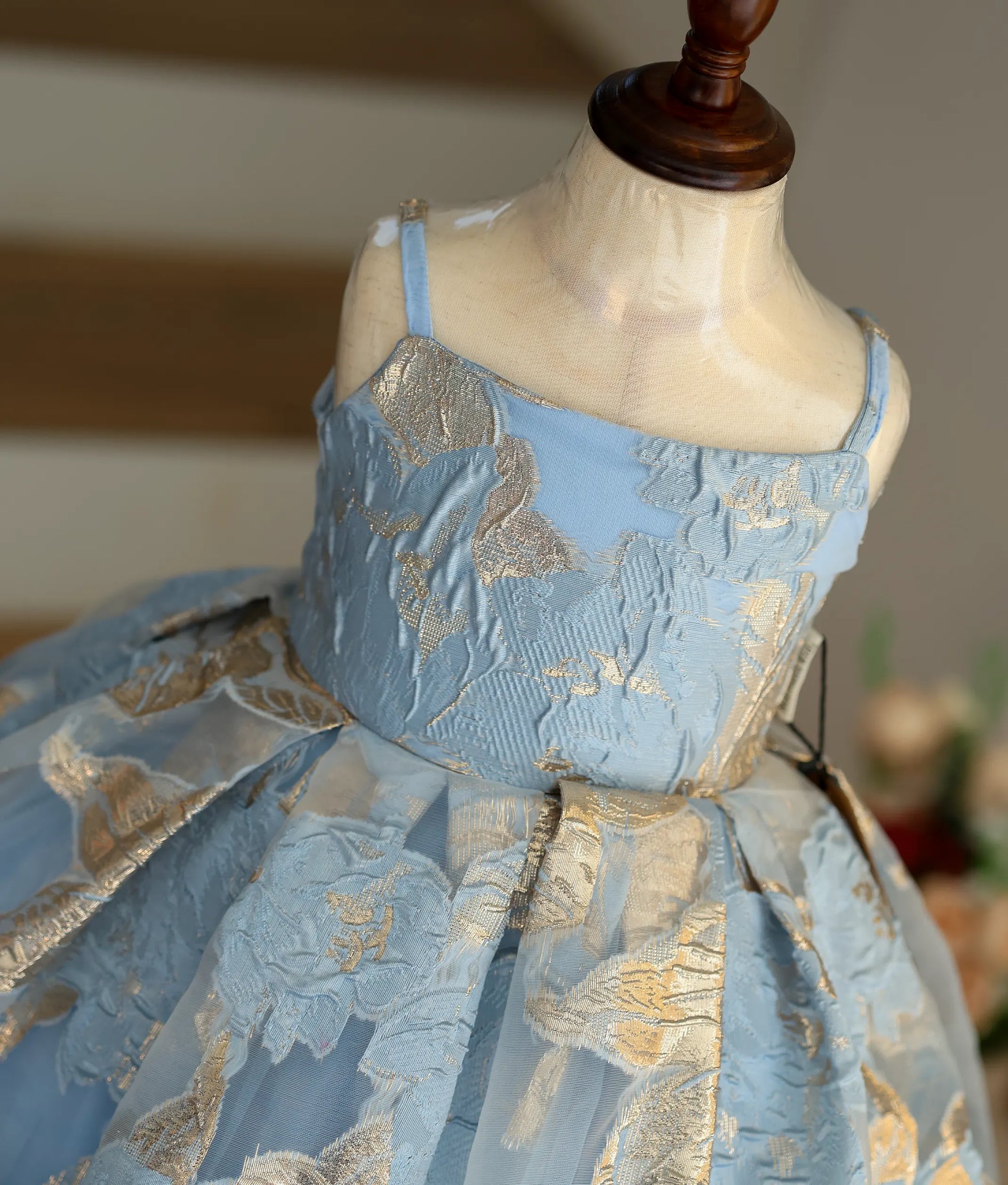 Close-up of the blue and gold floral patterns and square neck straps on the Turkish organza fabric.