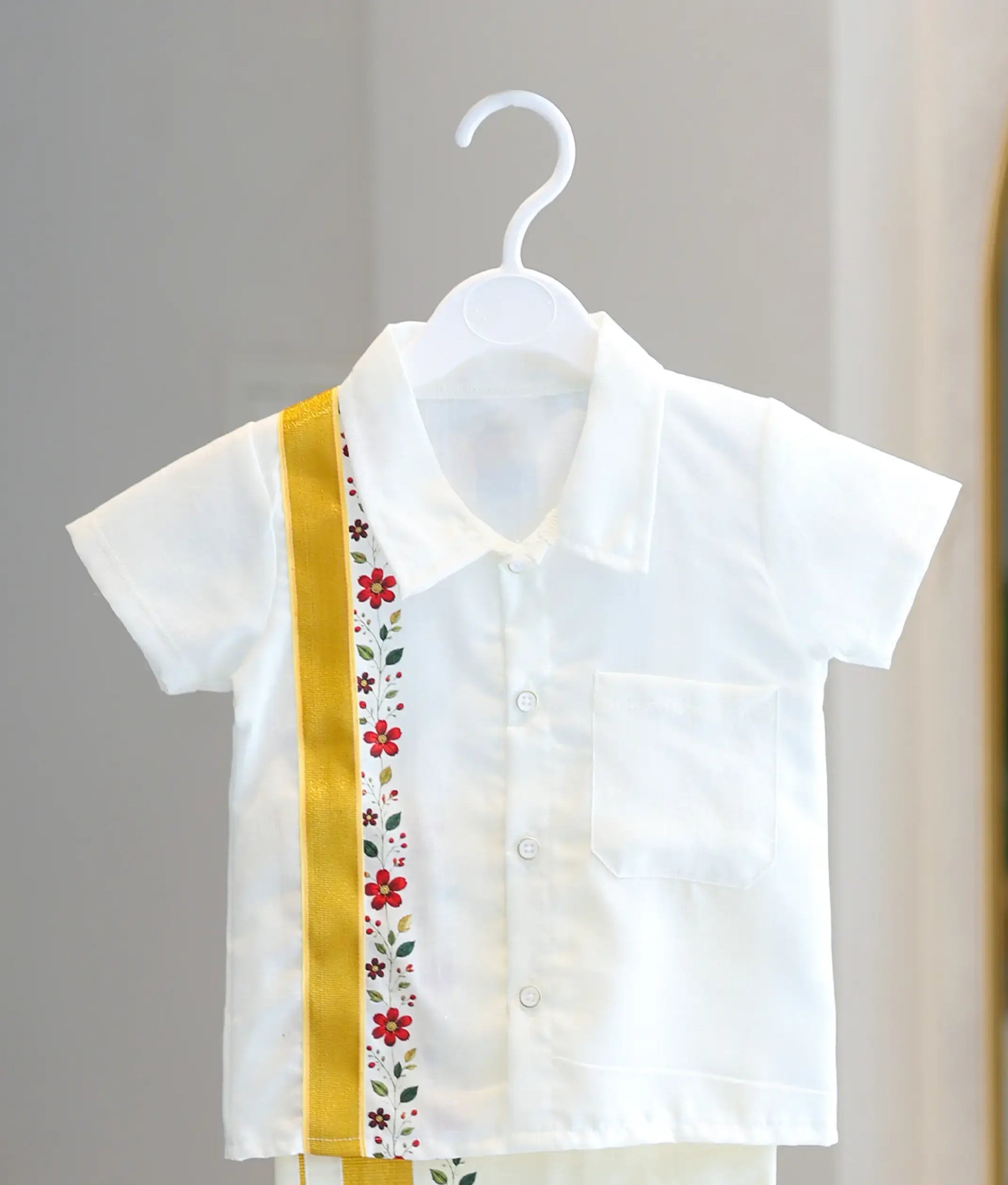 Front view of the boys off-white cotton shirt showing the resort collar, chest pocket, and vertical gold zari strip with floral print.