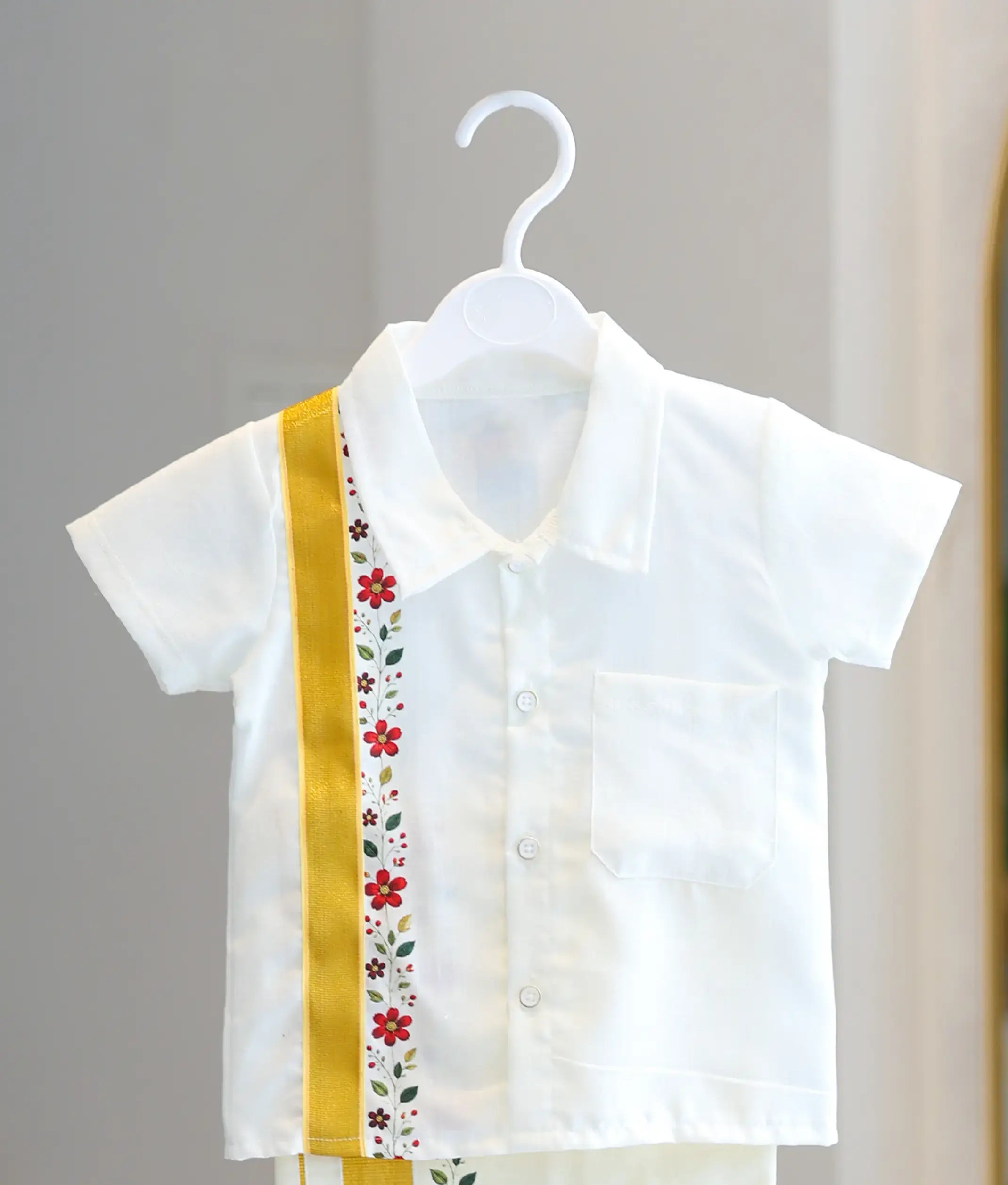 Front view of the boys off-white cotton shirt showing the resort collar, chest pocket, and vertical gold zari strip with floral print.