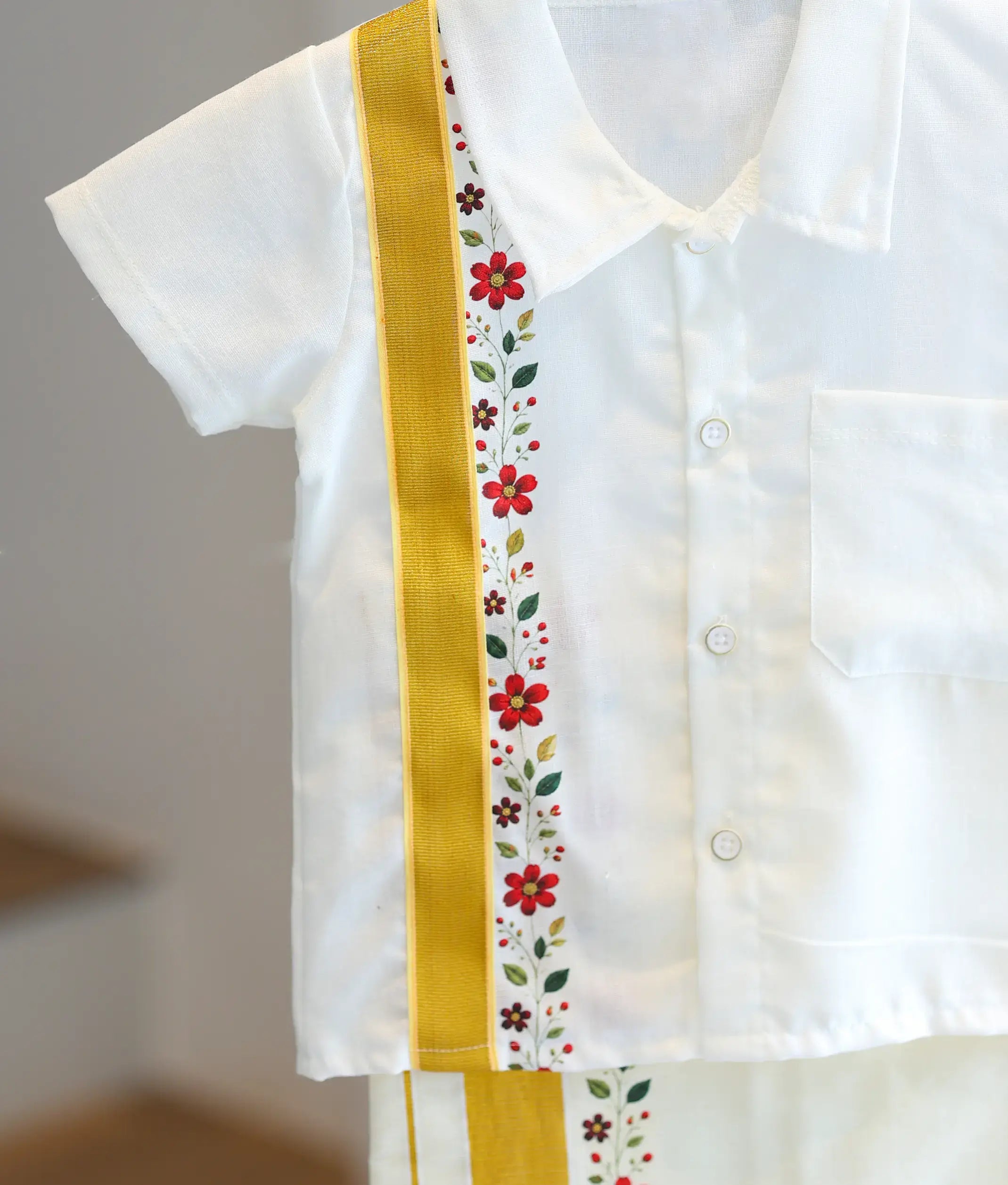 Close-up detail of the off-white cotton shirt panel featuring the gold zari border and printed floral pattern.